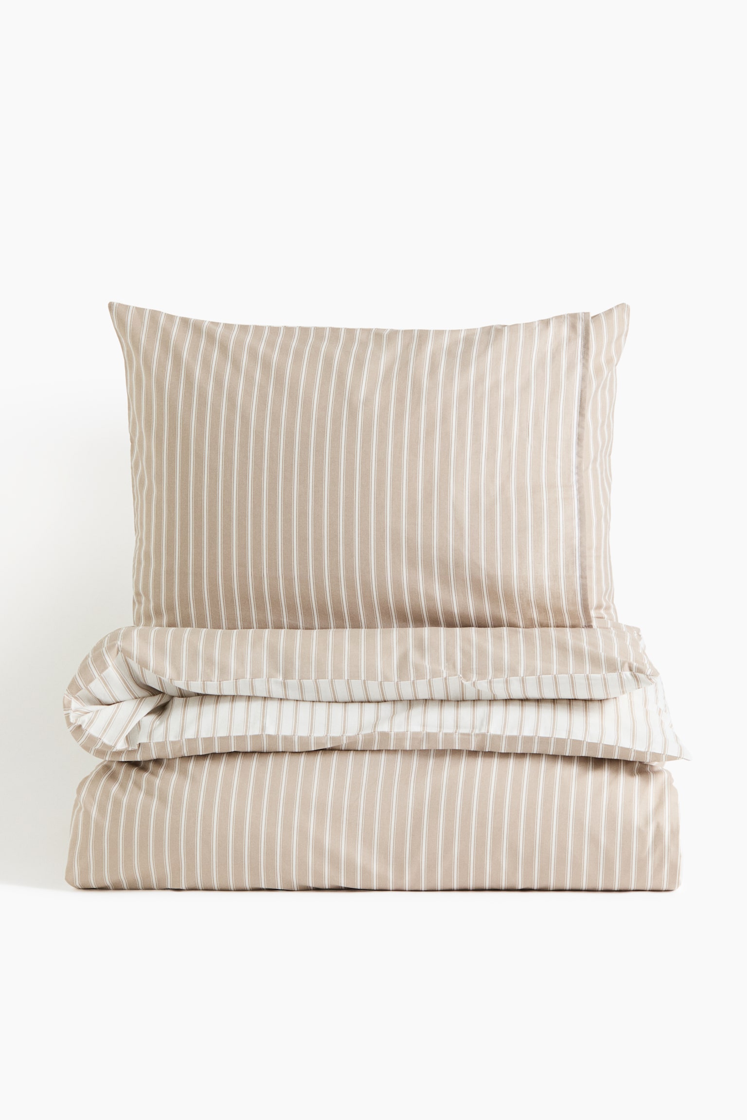 A beige and white striped duvet cover set is standing in a neat stack, featuring a matching pillowcase positioned upright behind a folded duvet cover. The front of the fabric is displaying thin white vertical stripes on a light beige base, while a folded edge is showing the contrasting reverse side with wider white stripes.