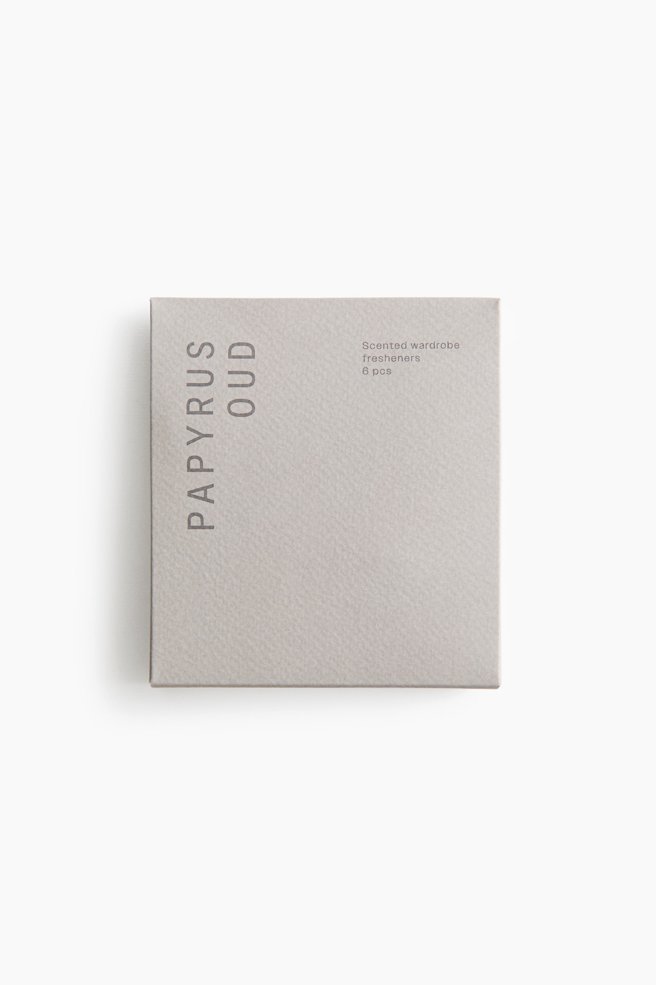 Grotere afbeelding bekijken: Een lichtgrijze, vierkante papieren pouch met geparfumeerde kledingkastverfrissers wordt van voren getoond, met een gestructureerd oppervlak. Op de pouch staat links de verticale tekst 'PAPYRUS OUD' en rechtsboven 'Geurige kledingkastverfrissers 6 stuks'.