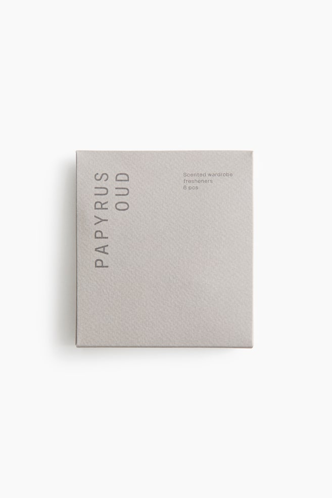 A light gray, square paper pouch containing scented wardrobe fresheners is shown from the front, displaying a textured surface. The pouch features the vertical text "PAPYRUS OUD" printed on the left side and "Scented wardrobe fresheners 6 pcs" on the upper right. - 1