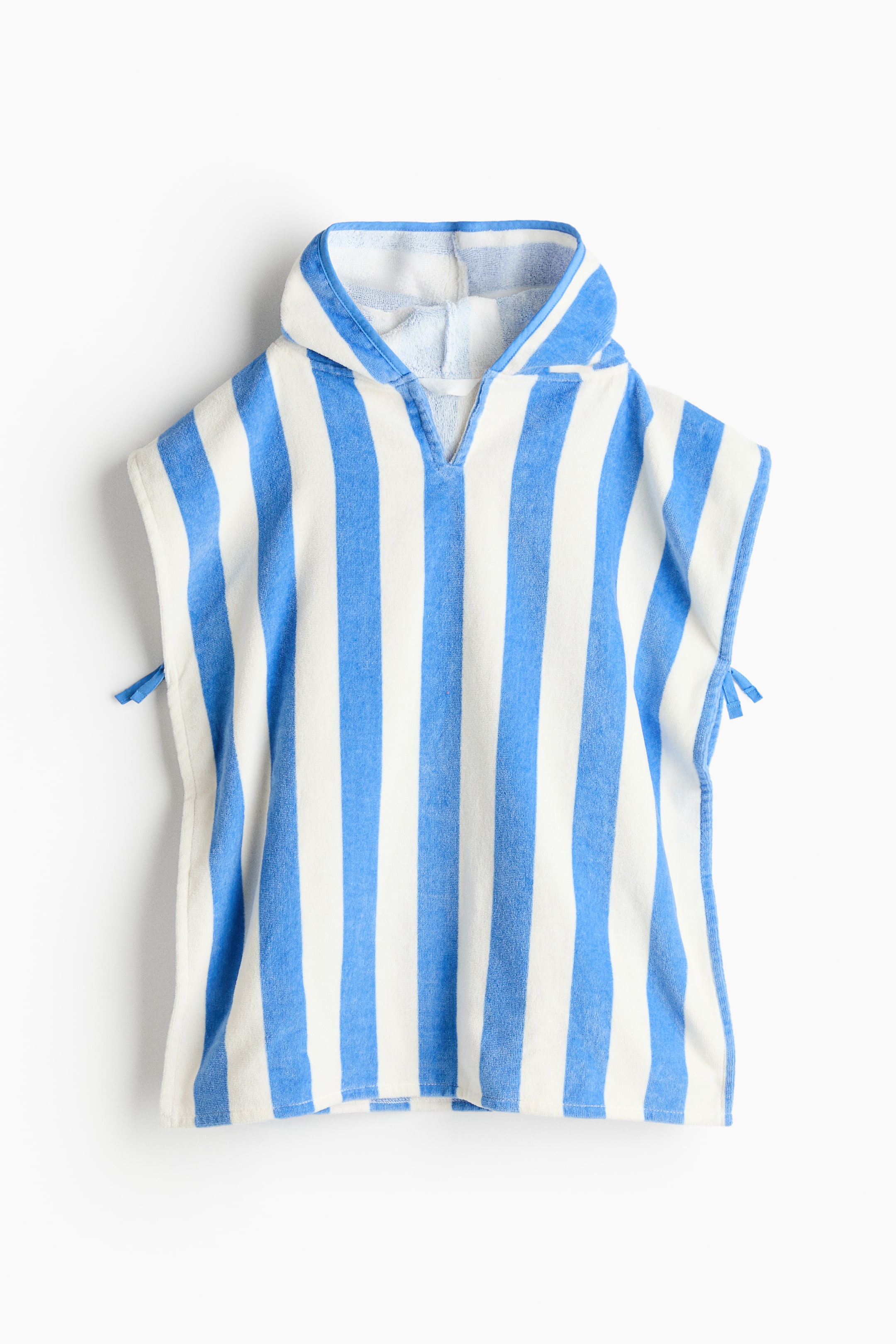 View larger image: A hooded poncho, crafted from blue and white vertical striped terry cloth, showcases a V-neck opening with small blue ties adorning each side.