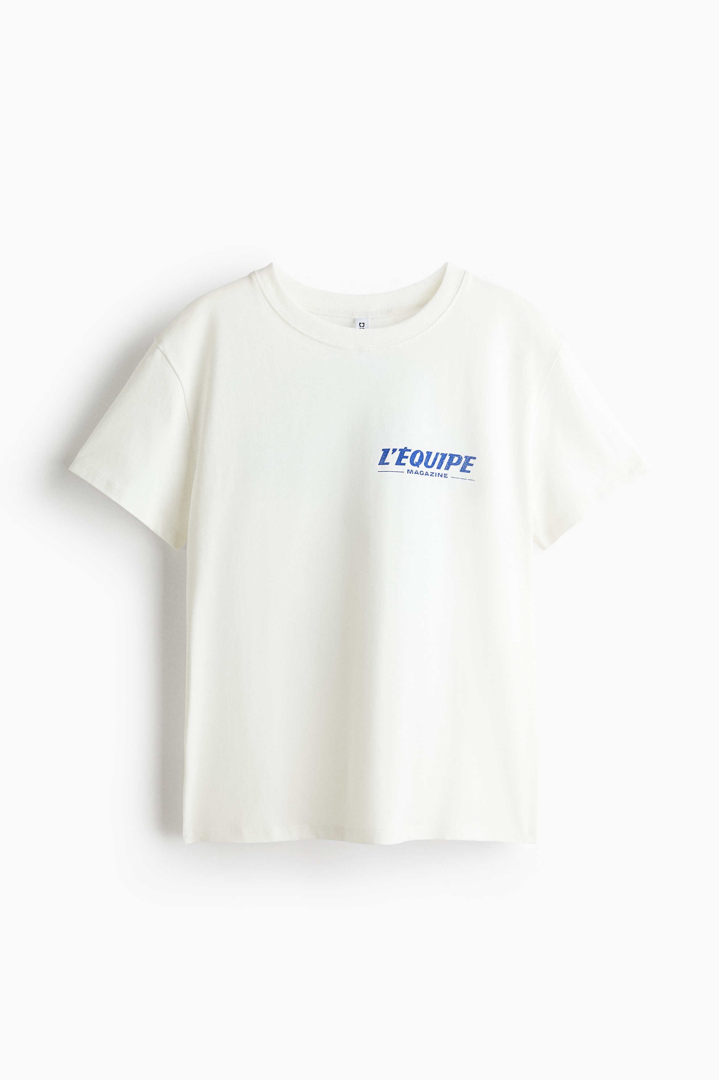Má»t chiáº¿c Ã¡o thun dÃ¡ng rá»ng báº±ng jersey cotton mÃ u tráº¯ng ngÃ  Äang táº¡o nÃªn phom dÃ¡ng thoáº£i mÃ¡i khi nhÃ¬n tá»« phÃ­a trÆ°á»c, vá»i cá» trÃ²n bo gÃ¢n, vai xuÃ´i vÃ  há»a tiáº¿t chá»¯ in mÃ u xanh nhá» trÃªn ngá»±c. Ão ÄÆ°á»£c tháº£ rá»§ tá»± nhiÃªn bÃªn ngoÃ i chÃ¢n vÃ¡y denim xanh nháº¡t, lÃ m ná»i báº­t kiá»u dÃ¡ng rá»ng rÃ£i, phÃ³ng khoÃ¡ng cá»§a sáº£n pháº©m.