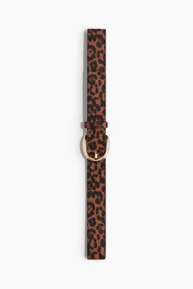 A leopard print belt with a textured finish is lying flat, featuring a rounded, gold-toned metal buckle with a single prong and a matching keeper loop. - 1