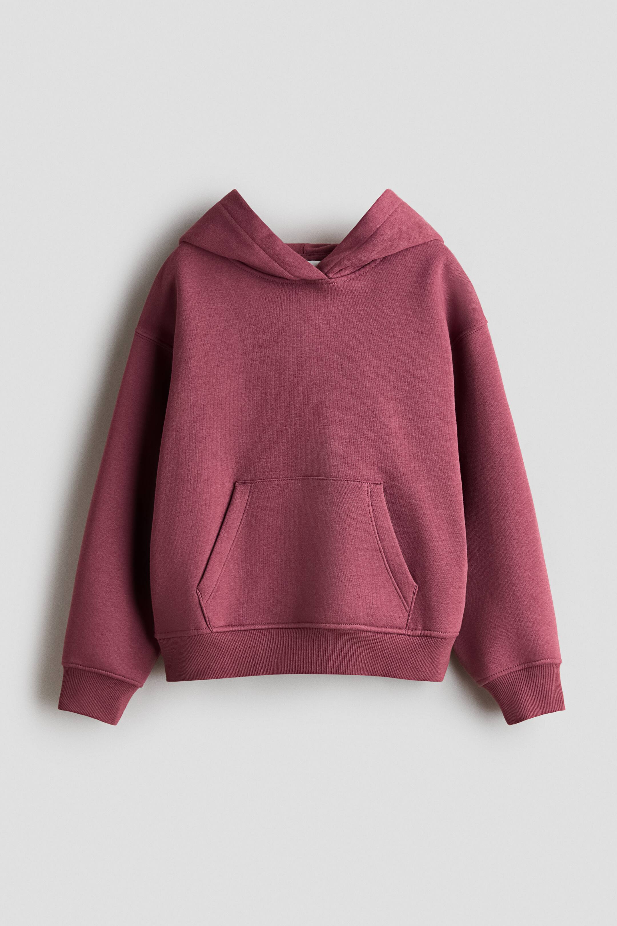 View larger image: A dusty rose hoodie is facing the front, showcasing a crossover wrap hood, dropped shoulders, and long sleeves with ribbed cuffs. The garment features a front kangaroo pocket and a ribbed hem.