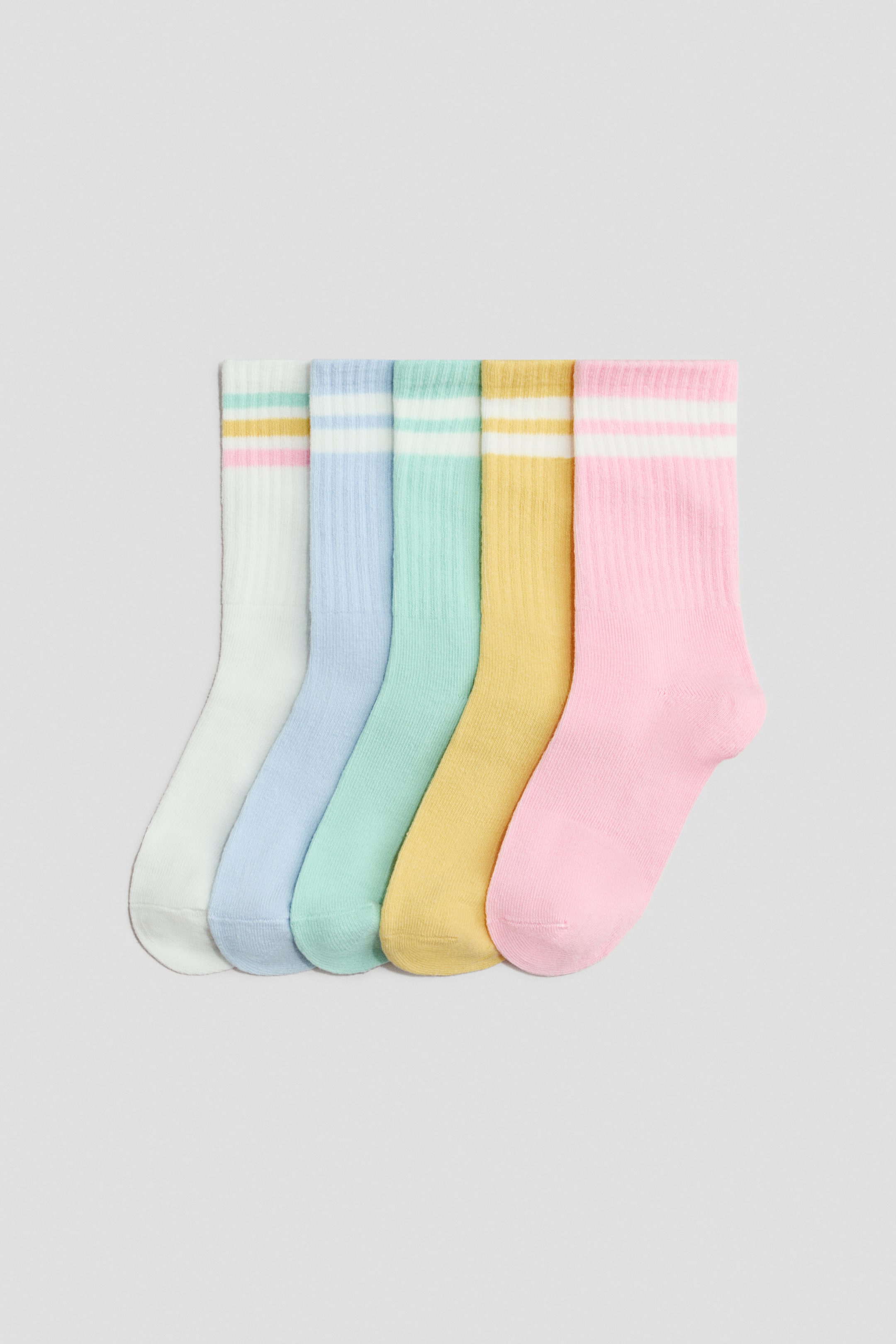 拡大画像を表示: 5足のファインニット靴下は、リブのシャフトと弾性トップ、トップ近くの2本の水平ストライプを特徴として、そのFRONT側を紹介しています。それらは、白、ライトブルー、ミントグリーン、ライトイエロー、ライトピンクのパステルカラーで登場しています。