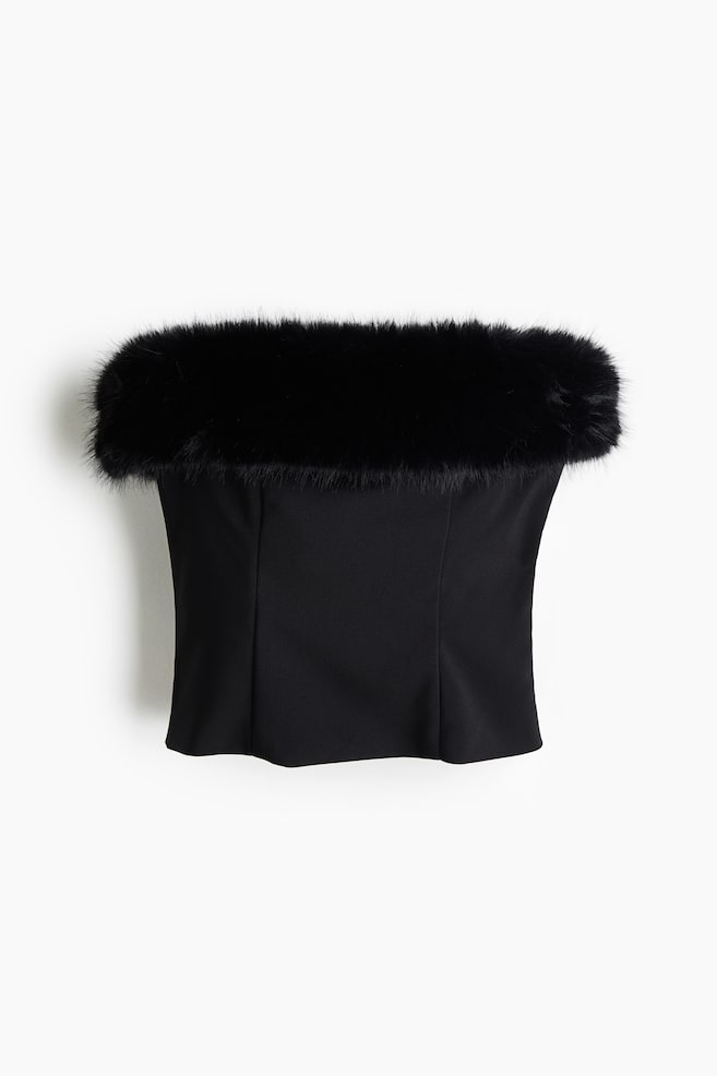 A black strapless top is shown from the front, featuring a plush black faux fur trim along its upper edge. The top's structured bodice is designed with vertical seams, creating a fitted silhouette. - 1