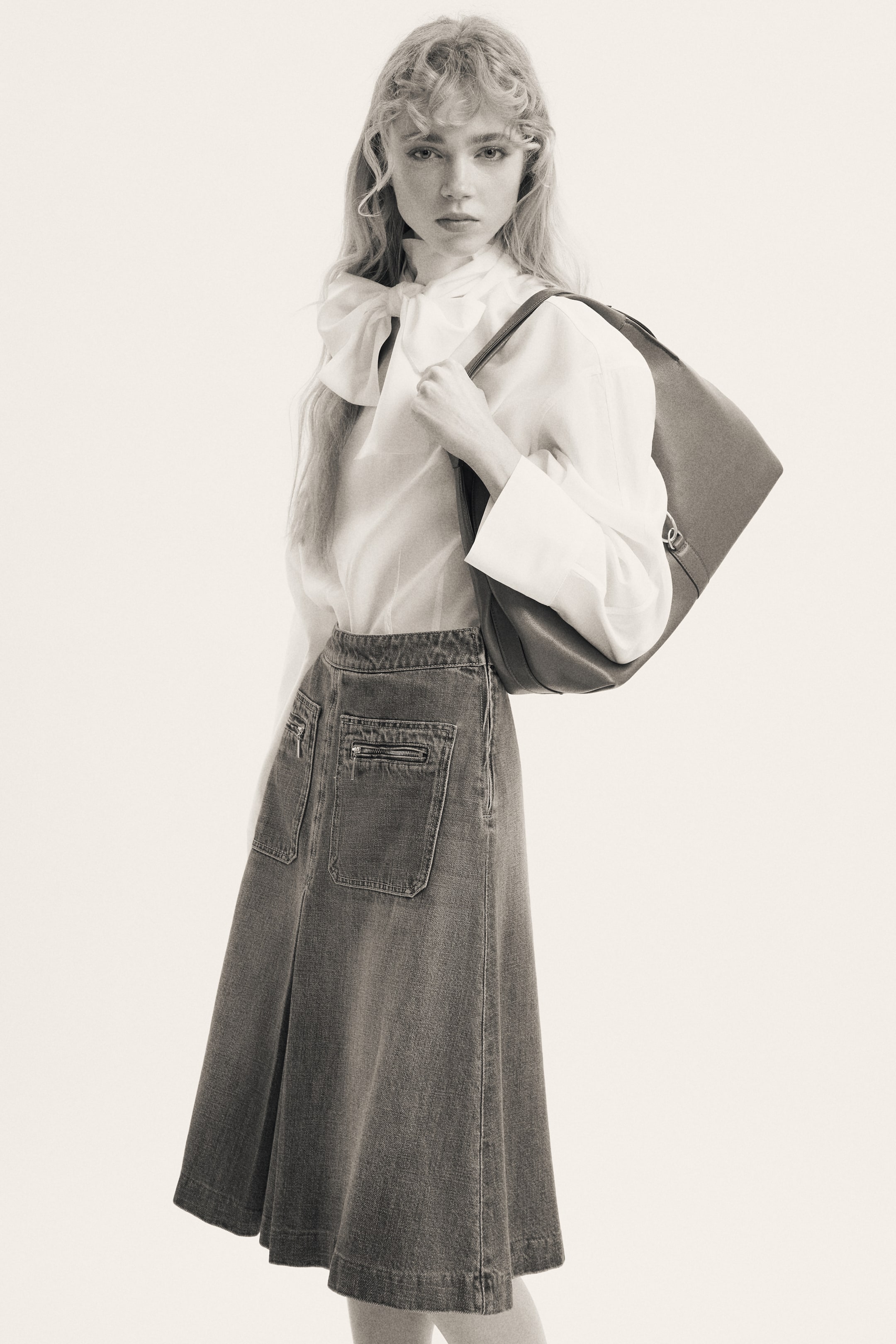 Προβολή μεγαλύτερης εικόνας: Το προϊόν είναι μια denim midi φούστα, εμφανιζόμενη σε προβολή τριών τετάρτων και ελαφρώς γωνιασμένη προς τα δεξιά. Διαθέτει καμπανοειδή σιλουέτα και δύο πίσω εφαρμοστές τσέπες με οριζόντιες λεπτομέρειες φερμουάρ.