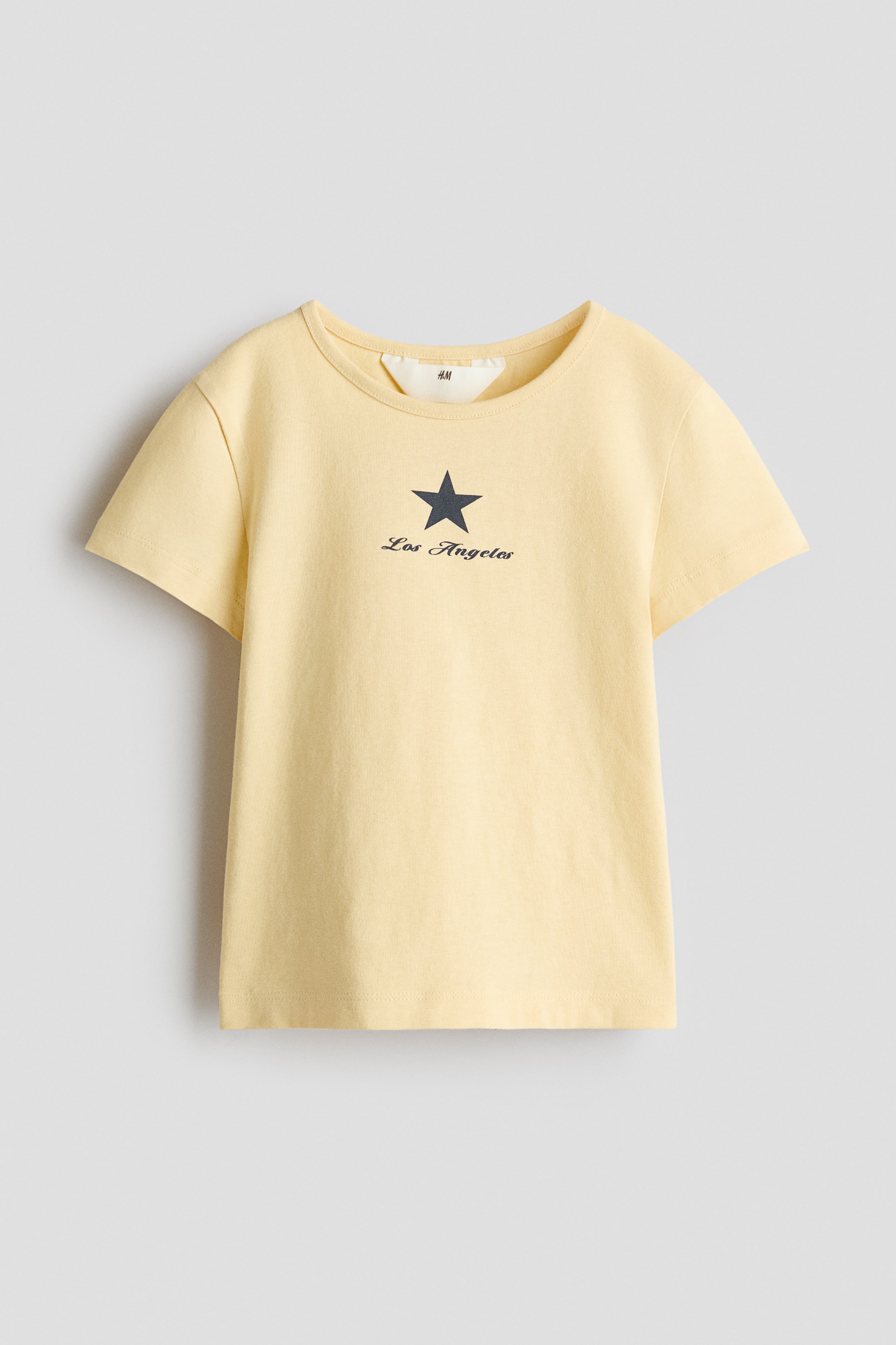 View larger image: It is featuring a round neck, short sleeves, and a dark grey star graphic centered on the chest with "Los Angeles" printed underneath in a script font.