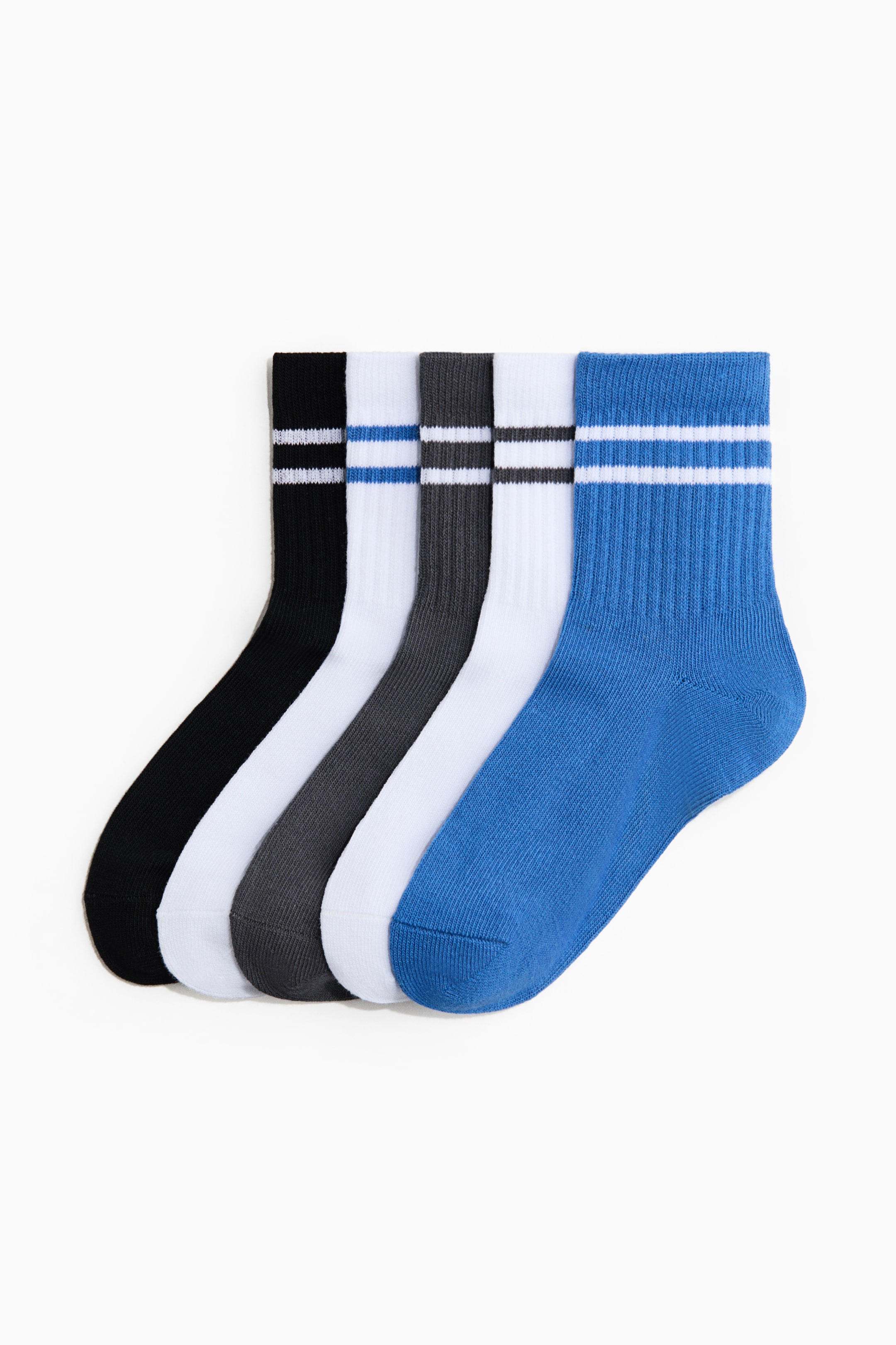 Agrandir l'image: Un lot de 5 paires de chaussettes de sport est présenté de face, disposé côte à côte en éventail. Chaque chaussette présente un pied en maille lisse et une bordure côtelée avec deux bandes horizontales, se déclinant dans les couleurs suivantes : noir avec des bandes blanches, blanc avec des bandes bleues, gris foncé avec des bandes blanches, blanc avec des bandes gris foncé, et bleu avec des bandes blanches.