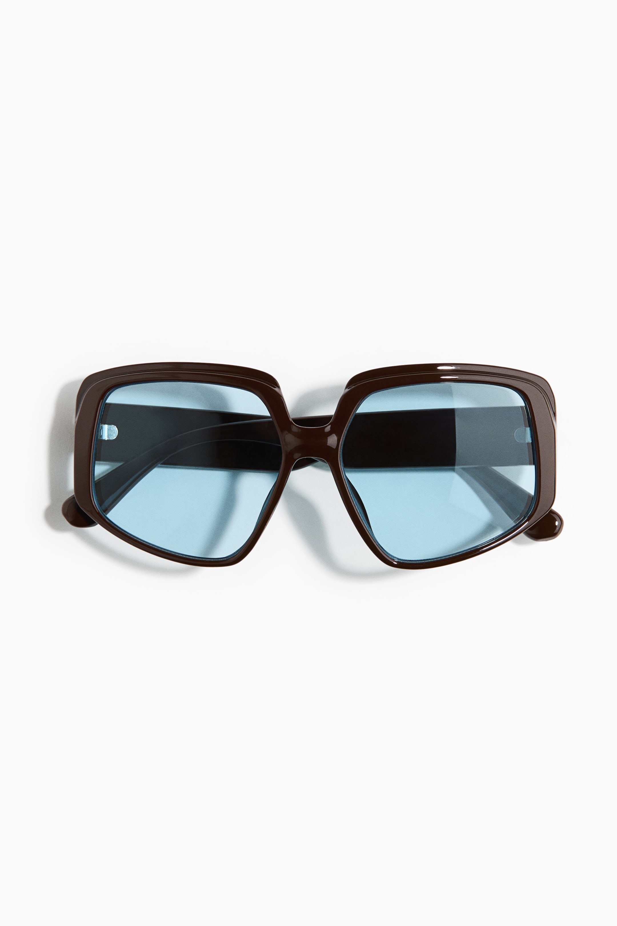 View larger image: The sunglasses boast a dark brown, oversized geometric frame paired with light blue tinted lenses, facing front.
