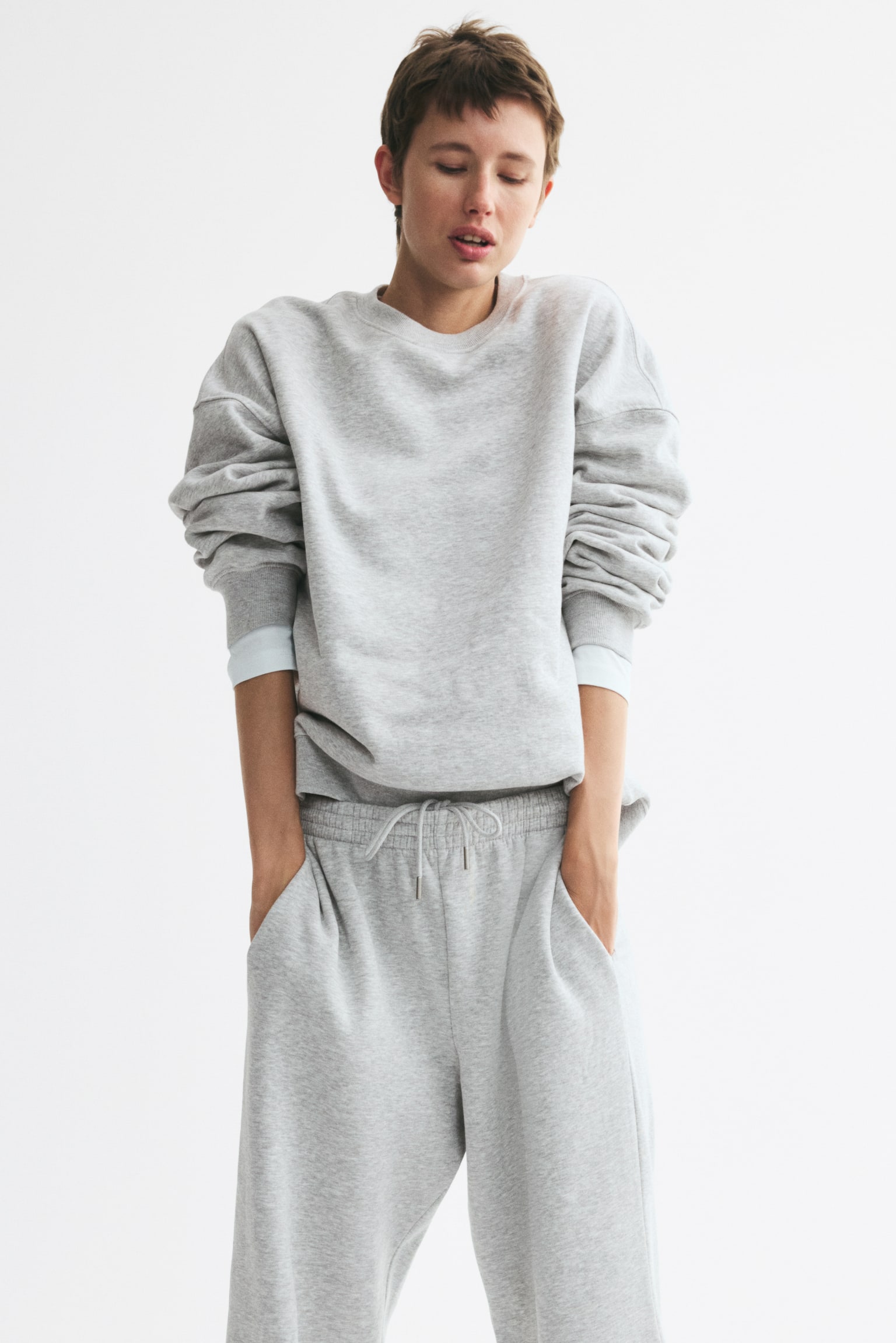 Light grey trackies are showcasing a front view, featuring an elasticated smocked waistband, side pockets, and straight legs in a marled sweatshirt fabric. - 1