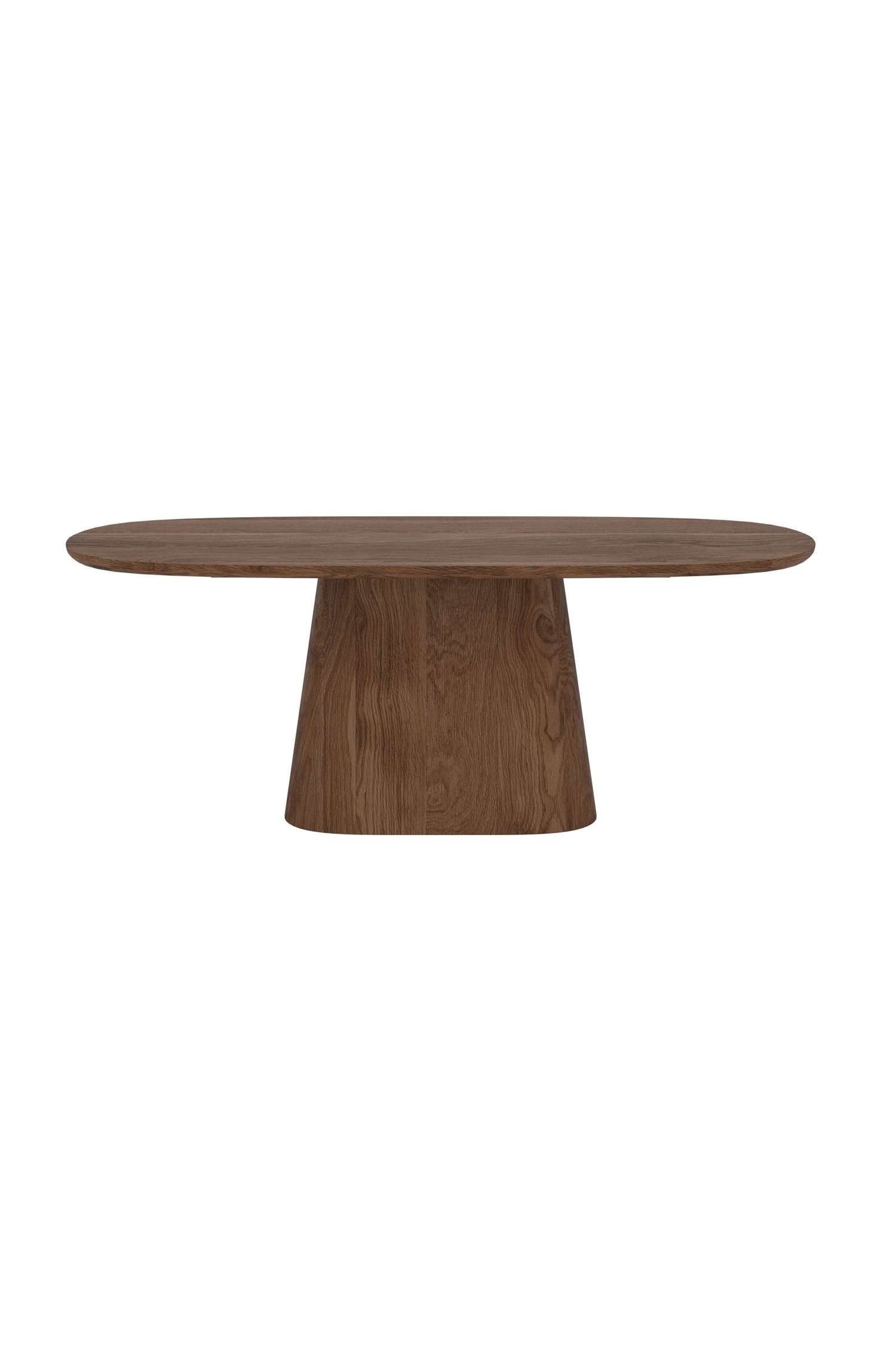 Una mesa de madera muestra una tapa ovalada y lisa apoyada sobre una base de pedestal gruesa y cÃ³nica, con una veta de madera natural muy marcada. Sobre la mesa hay un jarrÃ³n negro estriado con ramas secas y una pequeÃ±a escultura abstracta blanca.
