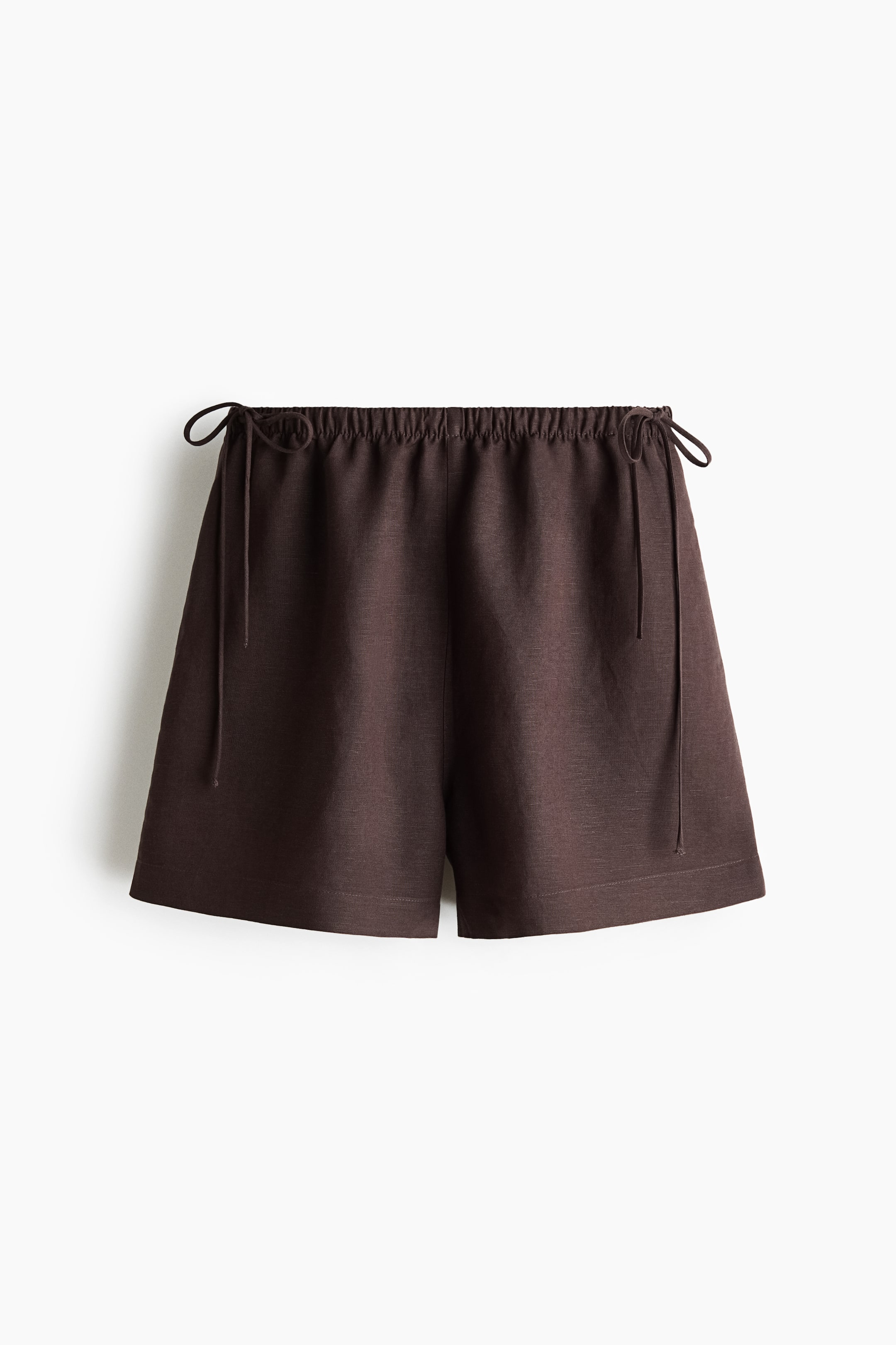 Visualizza immagine più grande: I pantaloncini marrone scuro sono mostrati in vista frontale. Presentano una cintura elasticizzata con due lacci annodati in piccoli fiocchi su ciascun lato e una vestibilità rilassata con orlo dritto.
