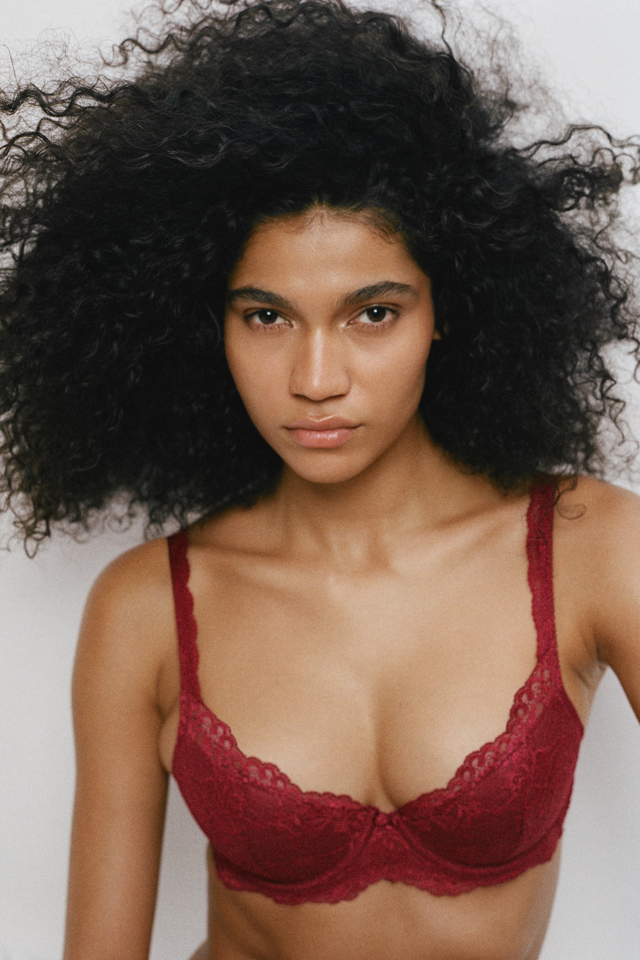 View larger image: A dark red lace push-up bra with underwired cups and scalloped lace trim is being worn by the model. The bra features slim, lace-covered shoulder straps.