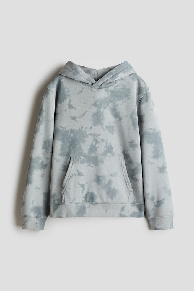 The hoodie is displayed from the front, crafted from printed sweatshirt fabric with a grey-green mottled pattern. It boasts a jersey-lined hood with a wrapover front, dropped shoulders, long sleeves, a kangaroo pocket, and ribbed cuffs and hem. - 1