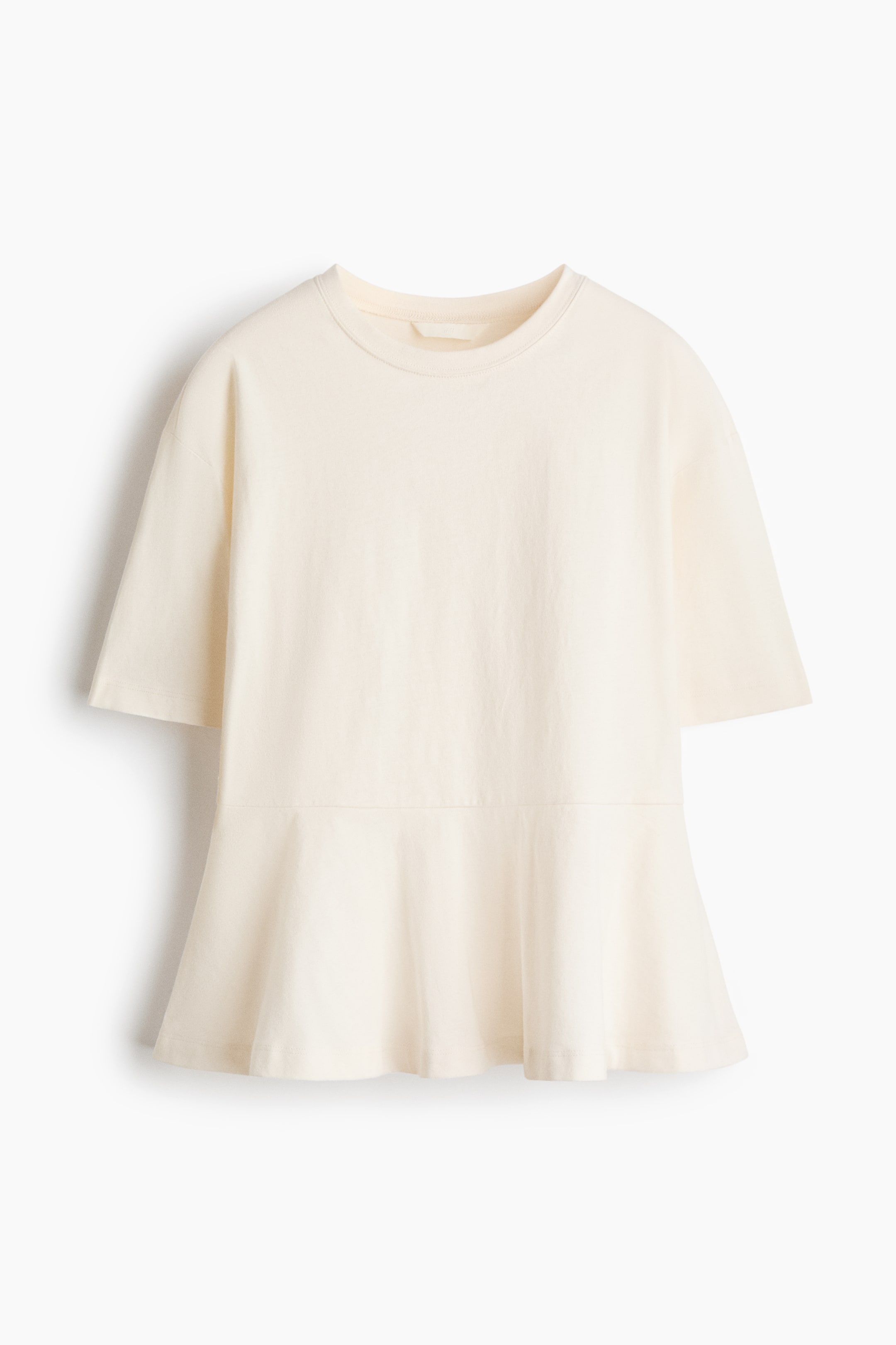View larger image: A cream top is shown in front view. It features a round neck, short sleeves, and a flared peplum hem starting from a horizontal seam.