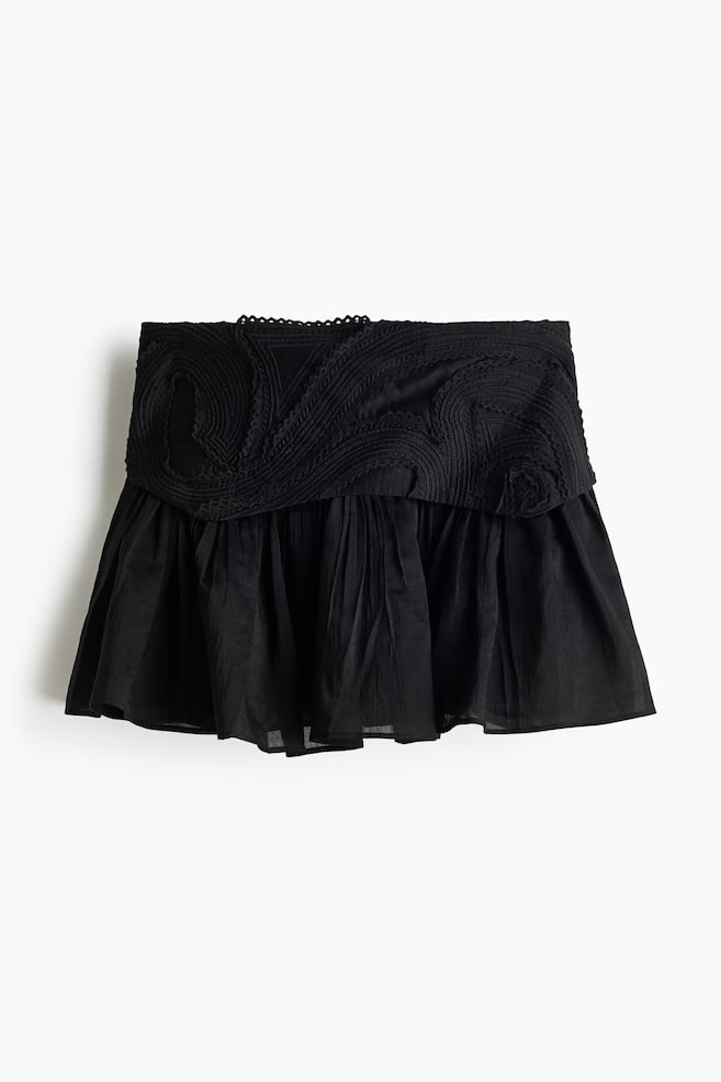 Der schwarze Minirock verfügt über einen breiten, eng anliegenden Bund mit erhabener, wirbelnder Stickerei und einer gewellten oberen Kante. Der untere Teil des Rocks präsentiert ein gerafftes, ausgestelltes Design aus einem geknitterten Stoff. - 1