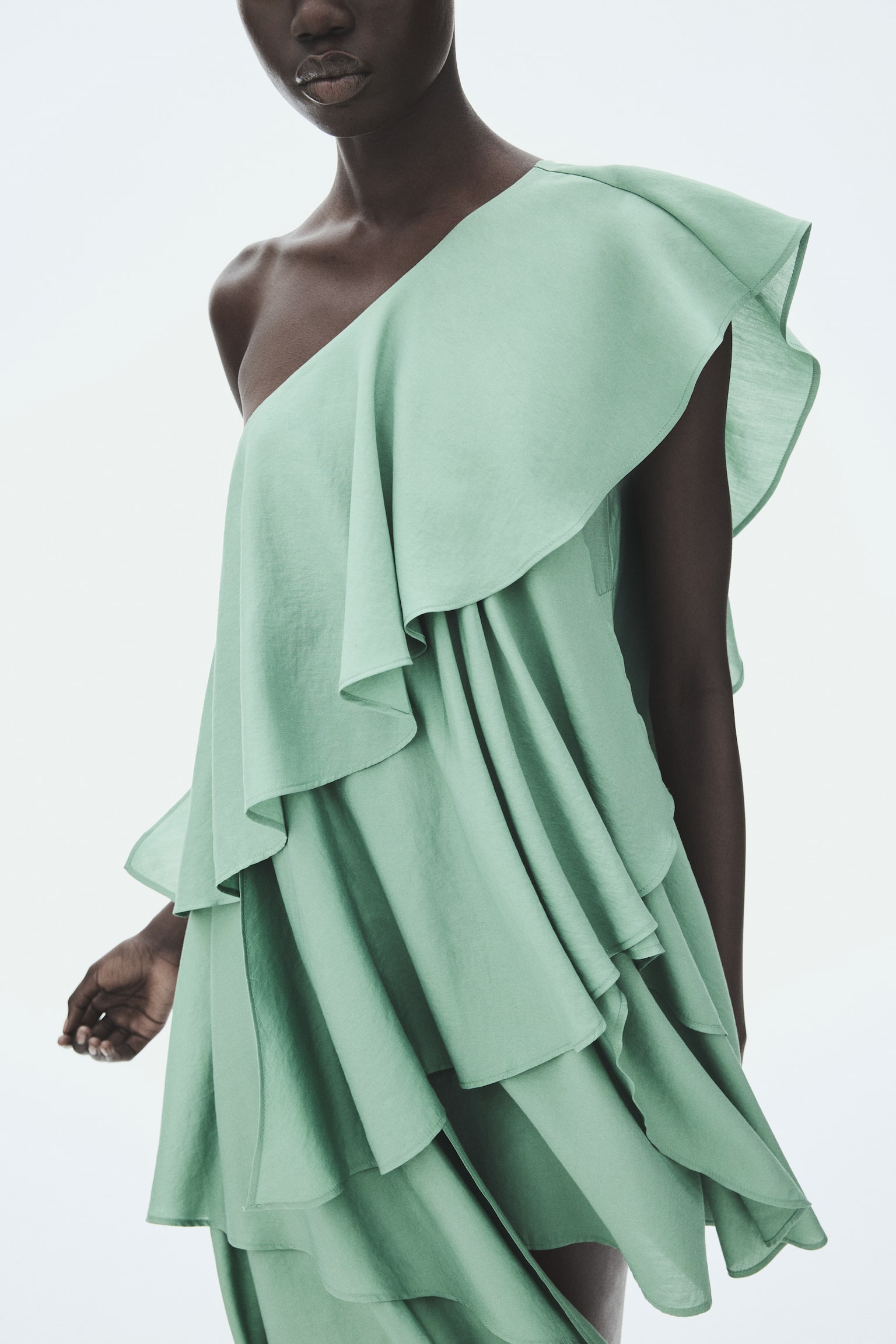 A sage green one-shoulder top showcasing multiple cascading ruffles and a draped, asymmetrical hem. - 1