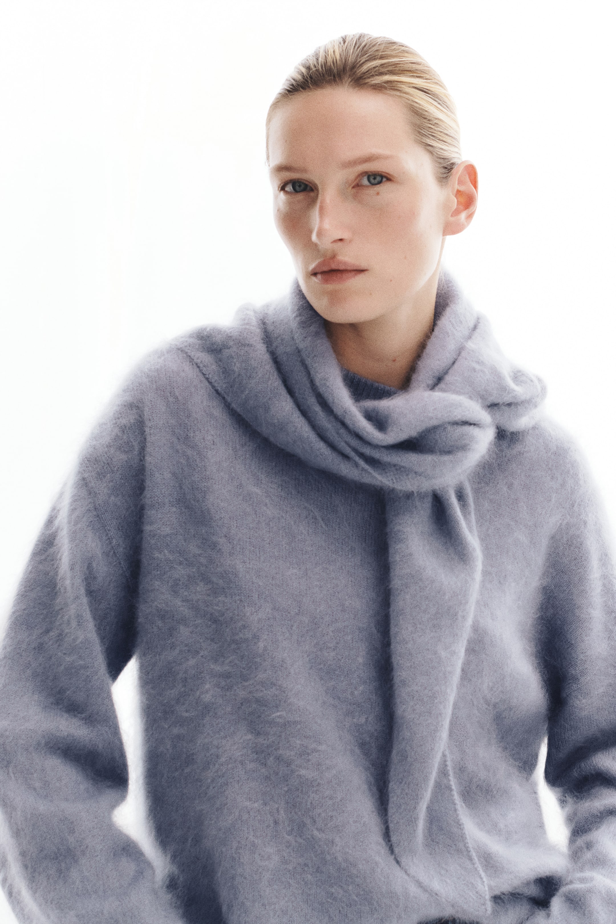 View larger image: A brushed wool-knit sweater in light blue-gray is being worn by the model, with a matching triangle scarf draped and loosely knotted around the neck. The sweater features a soft, fuzzy texture, dropped shoulders, and long sleeves.