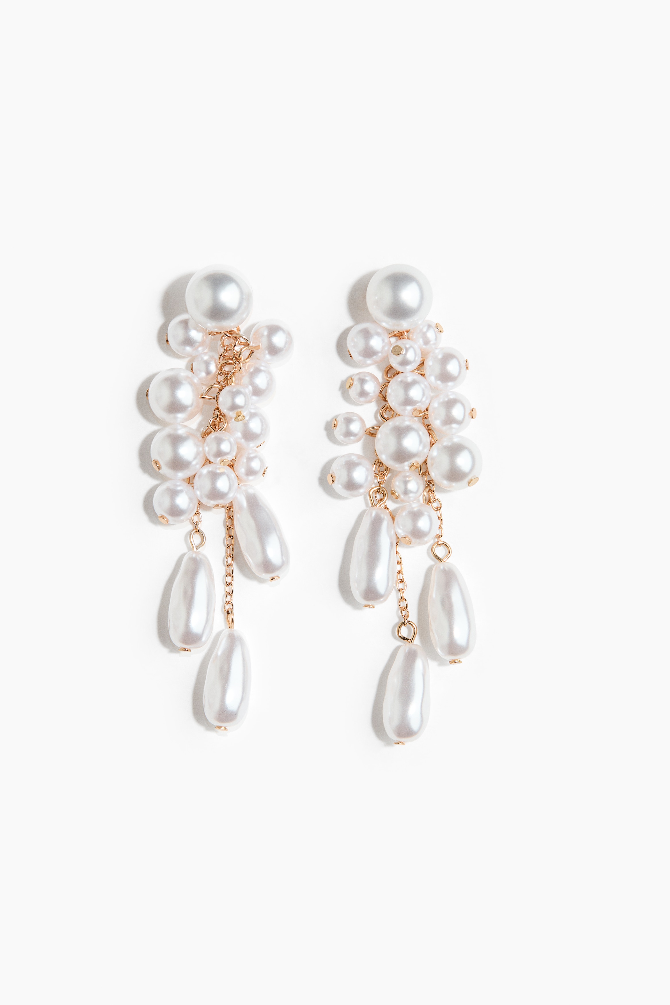 A drop earring featuring a cluster of round and teardrop-shaped pearlescent plastic beads on fine metal chains is being worn by the model. The earring hangs from the earlobe, resting against the high collar of a cream-coloured satin shirt.