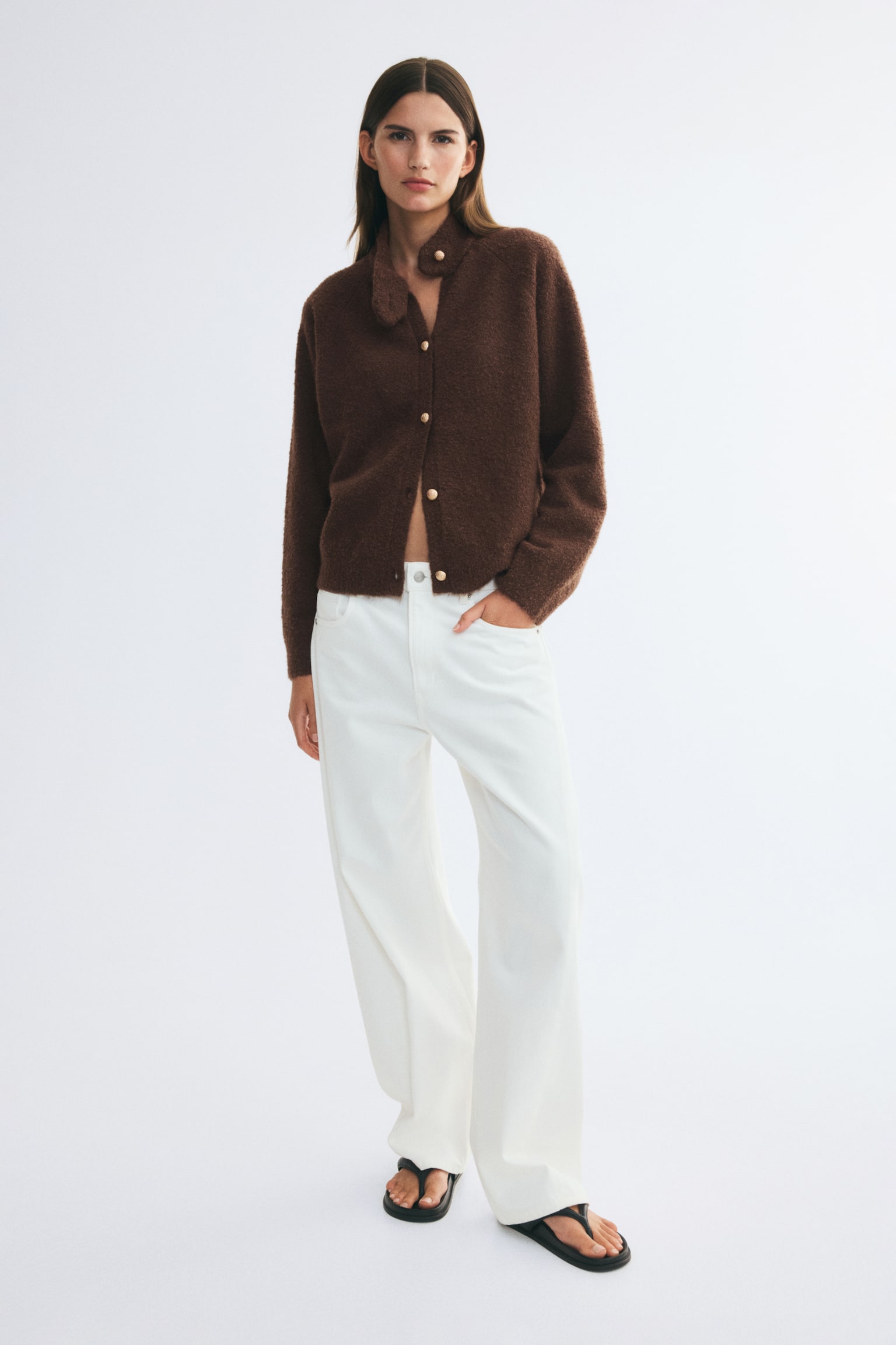 A dark brown, textured knit cardigan is facing front, showcasing a high mock neck with an asymmetrical buttoned tab and a front button closure with gold-toned dome buttons. The cardigan is featuring long raglan sleeves and a straight hem in a fuzzy, boucl�-like fabric. - 1