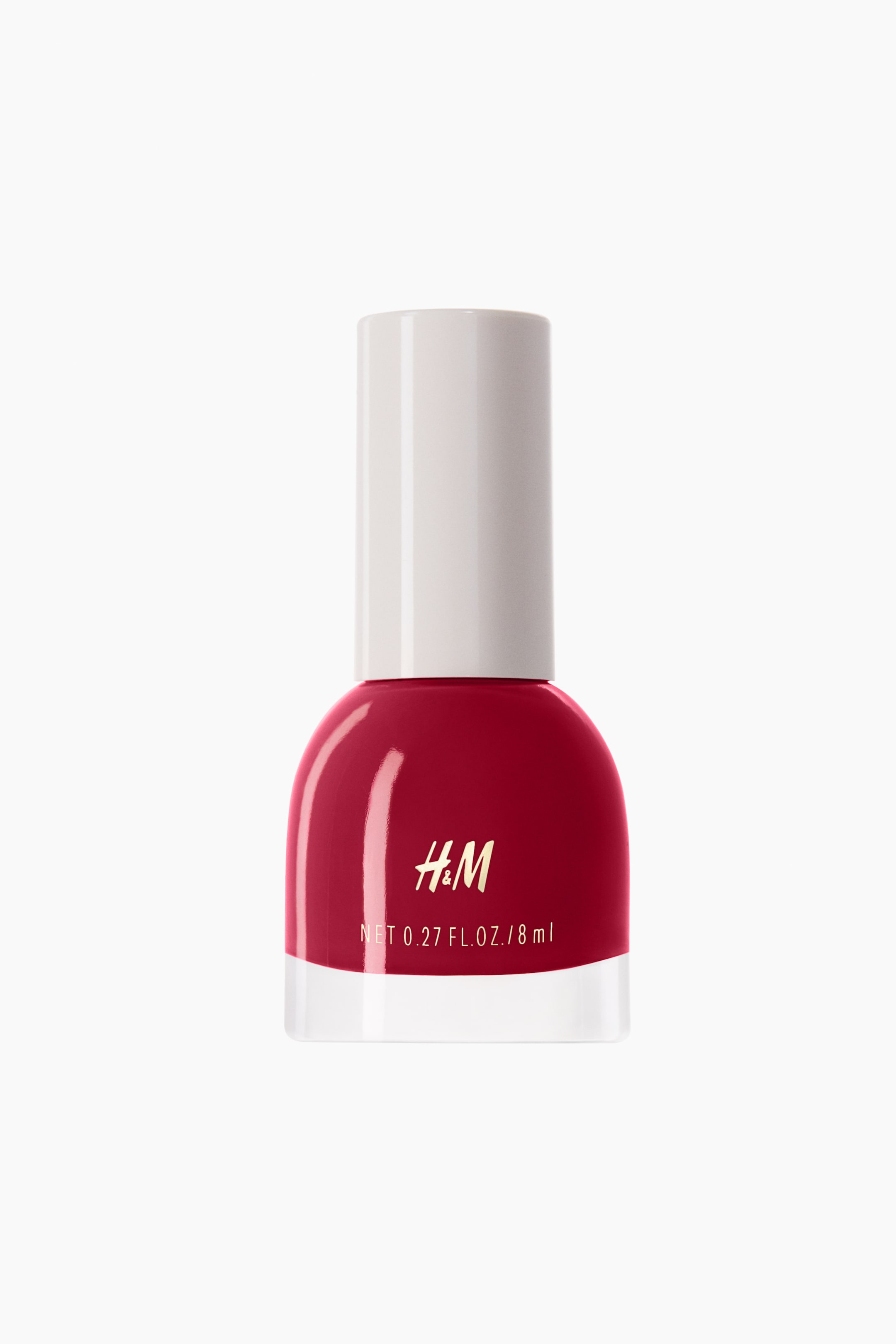 Grotere afbeelding bekijken: Een nagellakflesje staat naar voren gericht, met een heldere glazen fles met een ronde basis gevuld met een dieprode lak, en een cilindrische off-white dop. Het H&M-logo is in goud gedrukt op de voorkant, boven witte tekst die luidt 'NET 0.27 FL. OZ. / 8 ml'.