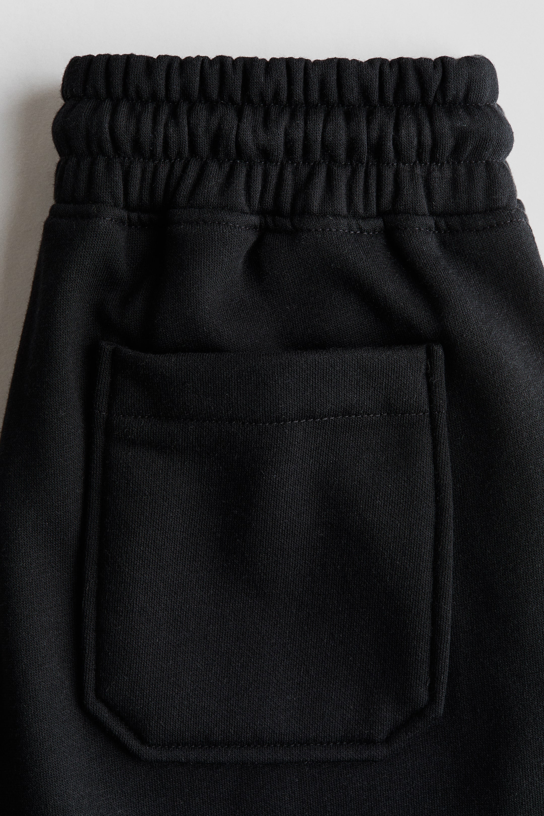 Größeres Bild ansehen: Schwarze Jogginghose aus Sweatshirtstoff mit gerafftem elastischem Bund und einer offenen Gesäßtasche.