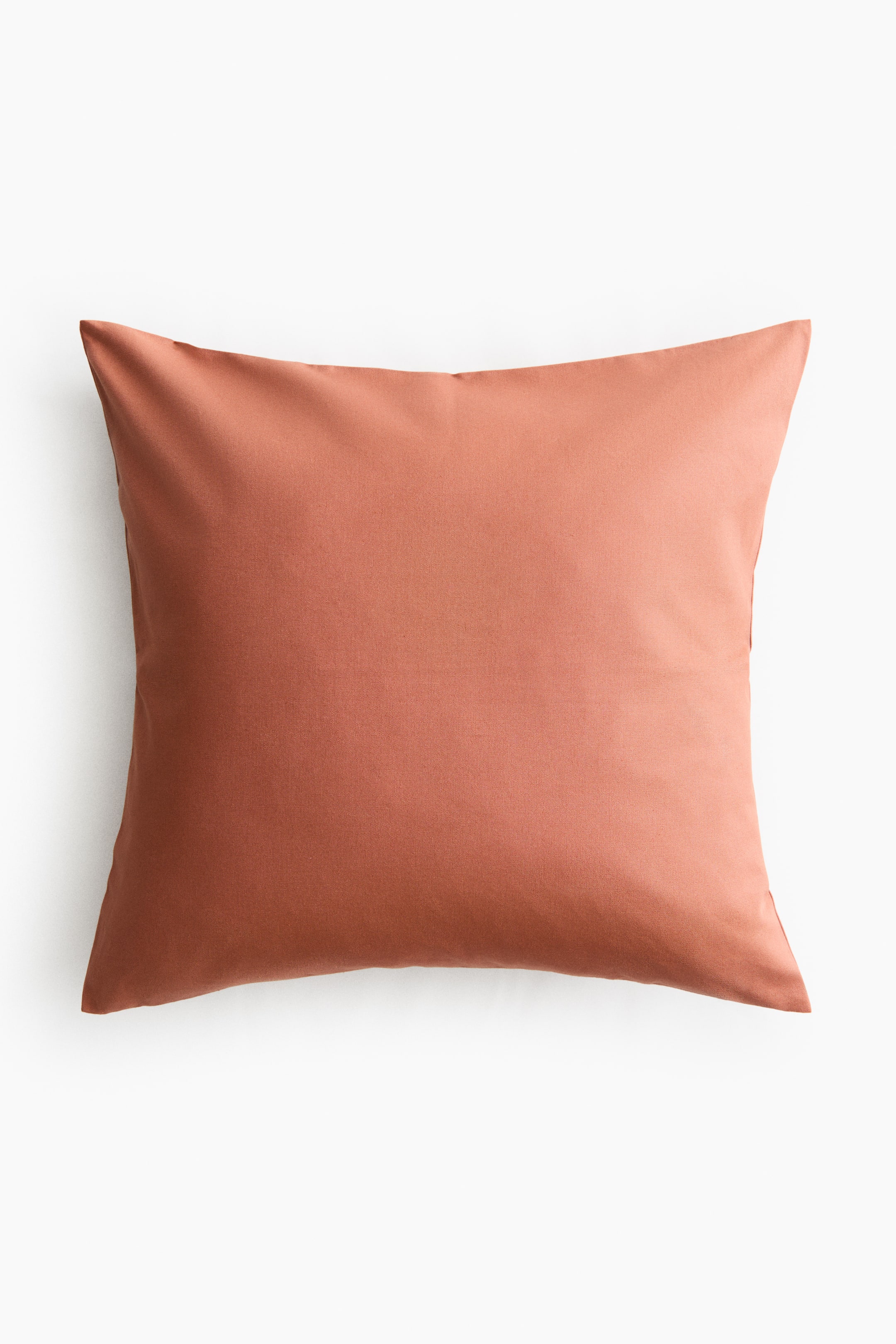 View larger image: A cushion cover is shown from the front, appearing plump and square-shaped in a muted reddish-orange colour. It displays a smooth, matte textile texture.