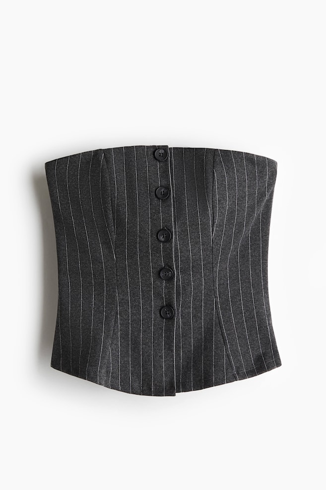 A dark gray pinstripe strapless top is featuring a column of five dark, round buttons down its center front, presenting a structured fit with vertical shaping seams and a slightly curved hemline. - 1