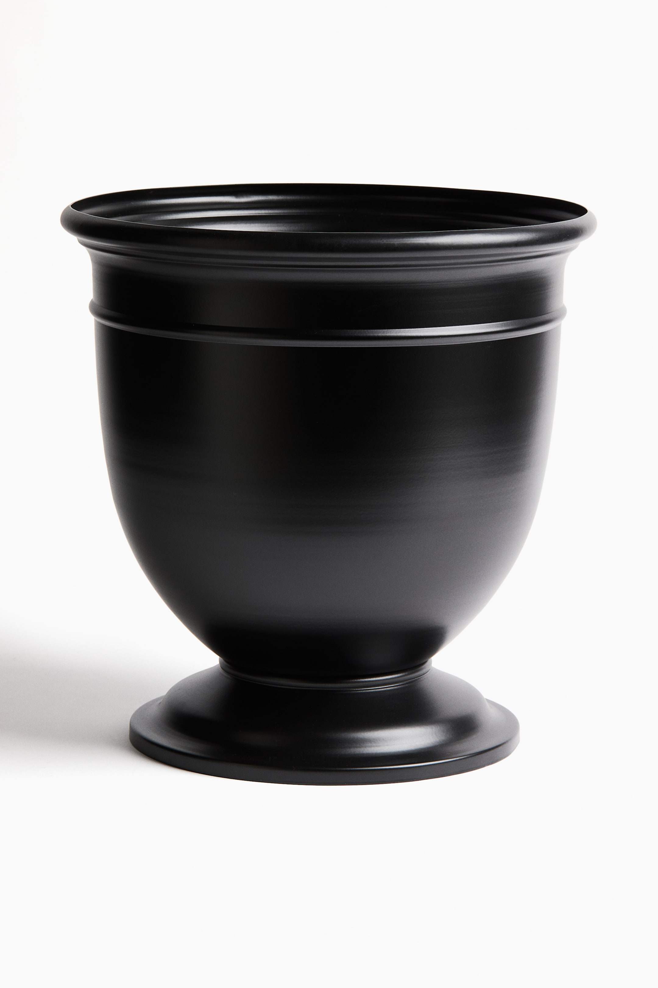 View larger image: A satin black planter featuring a wide, rounded rim with multiple horizontal ridges, its bowl-shaped body curving inwards to a flared, round pedestal base.
