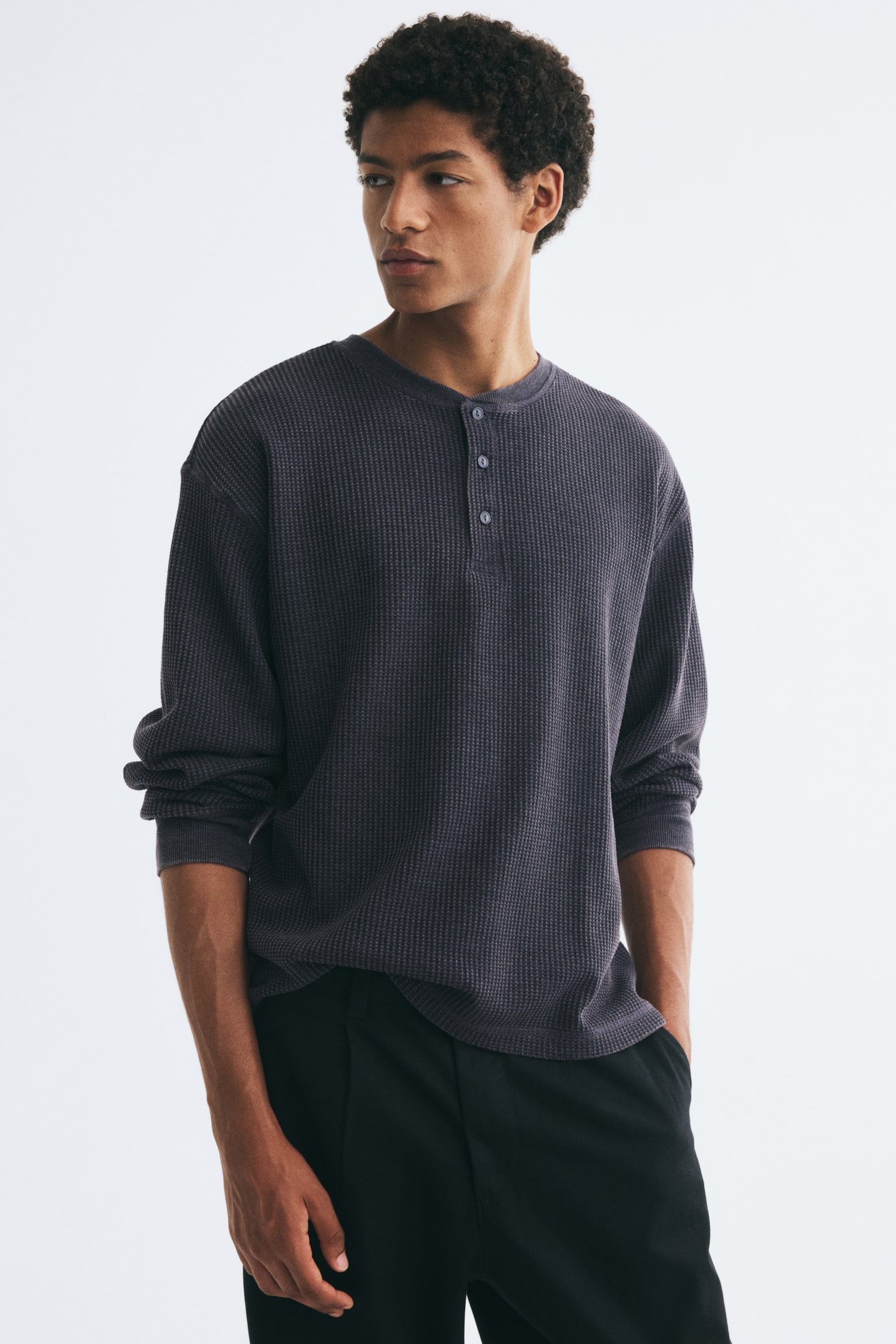 A dark gray waffle knit Henley shirt is shown in a front view, featuring a crew neck with a three-button placket and long sleeves with ribbed cuffs. - 1