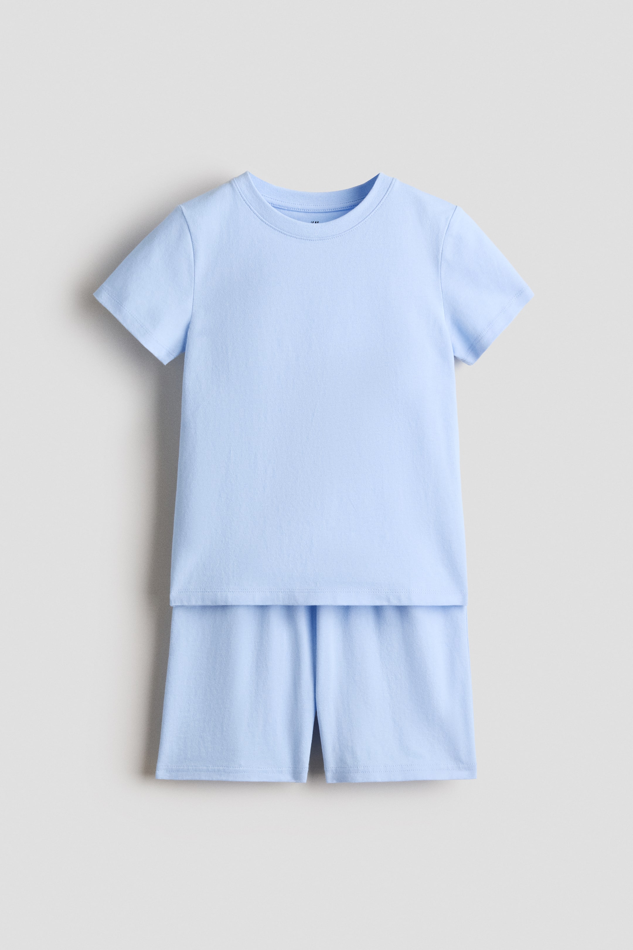 View larger image: A light blue T-shirt and shorts set is displayed front-facing. The T-shirt features a round, rib-trimmed neckline, short sleeves, and a straight-cut hem. The matching shorts showcase an elasticated, drawstring waist.