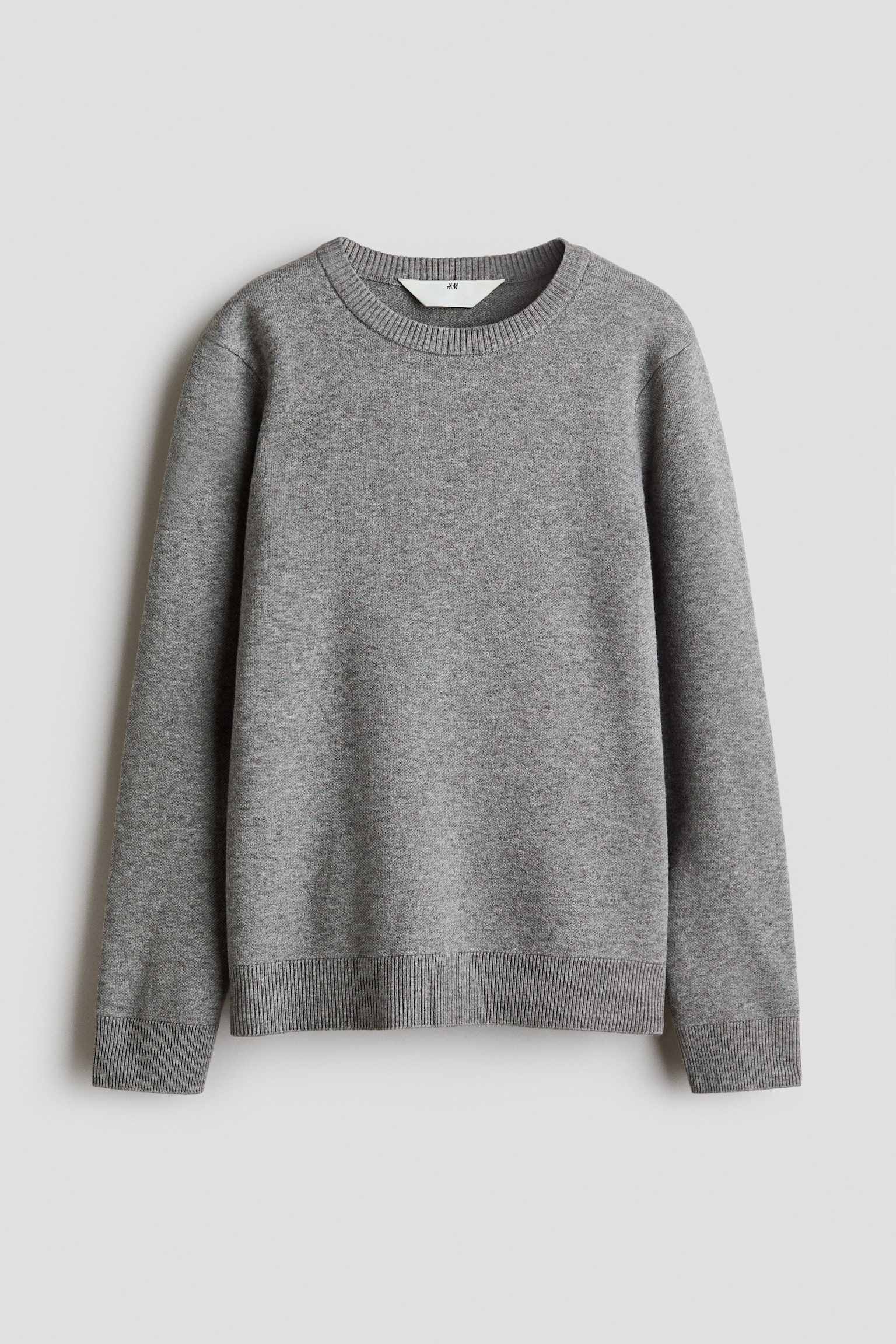 A grey, fine-knit sweater is shown from the front, featuring a classic crew neckline, long sleeves, and ribbed detailing around the neckline, cuffs, and hem.