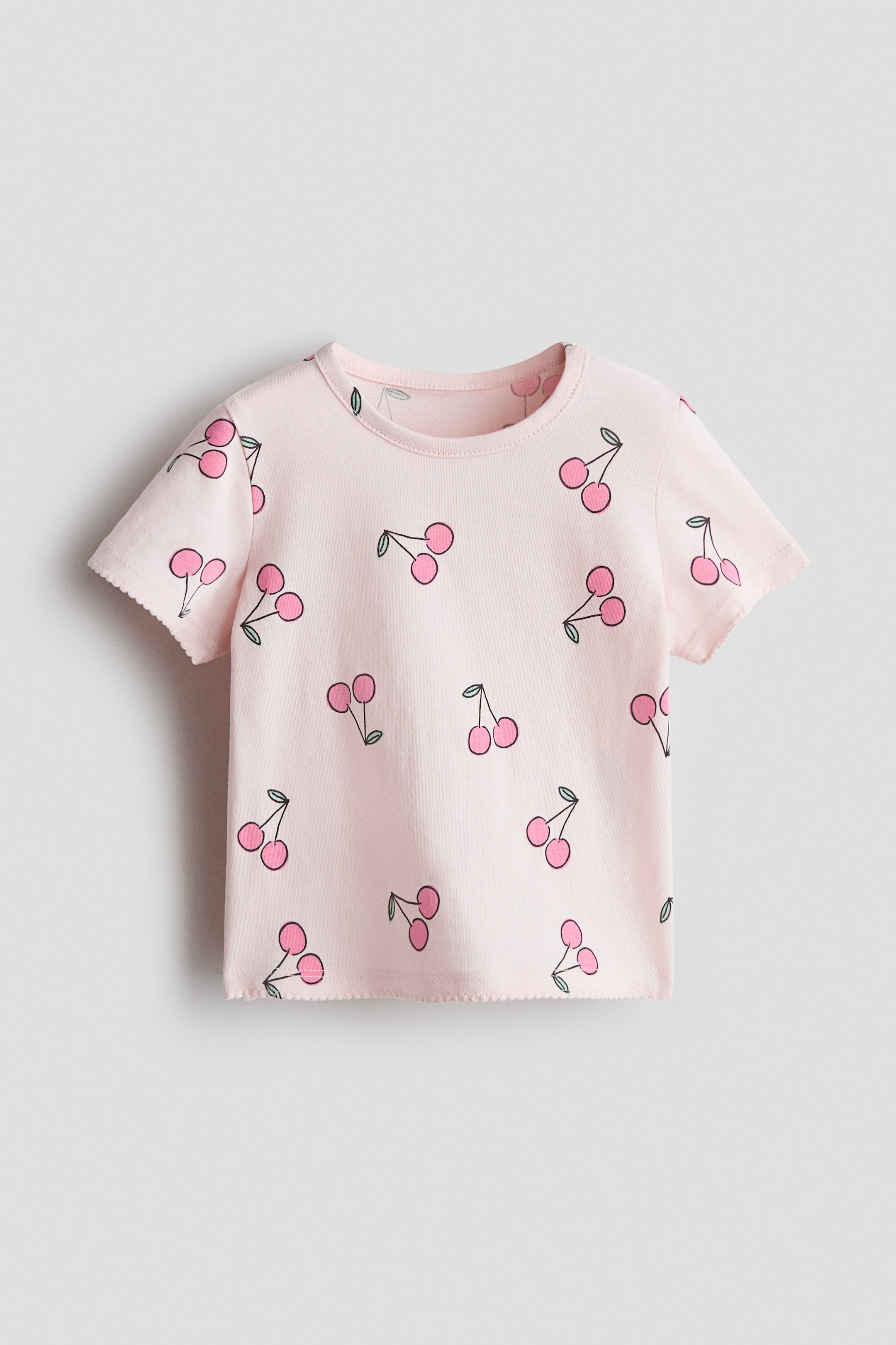Grotere afbeelding bekijken: Bedrukte katoenen top. Een lichtroze katoenen top met een herhalende kersenprint. Ontworpen met een ronde hals en geschulpte randen aan de korte mouwen en onderzoom.