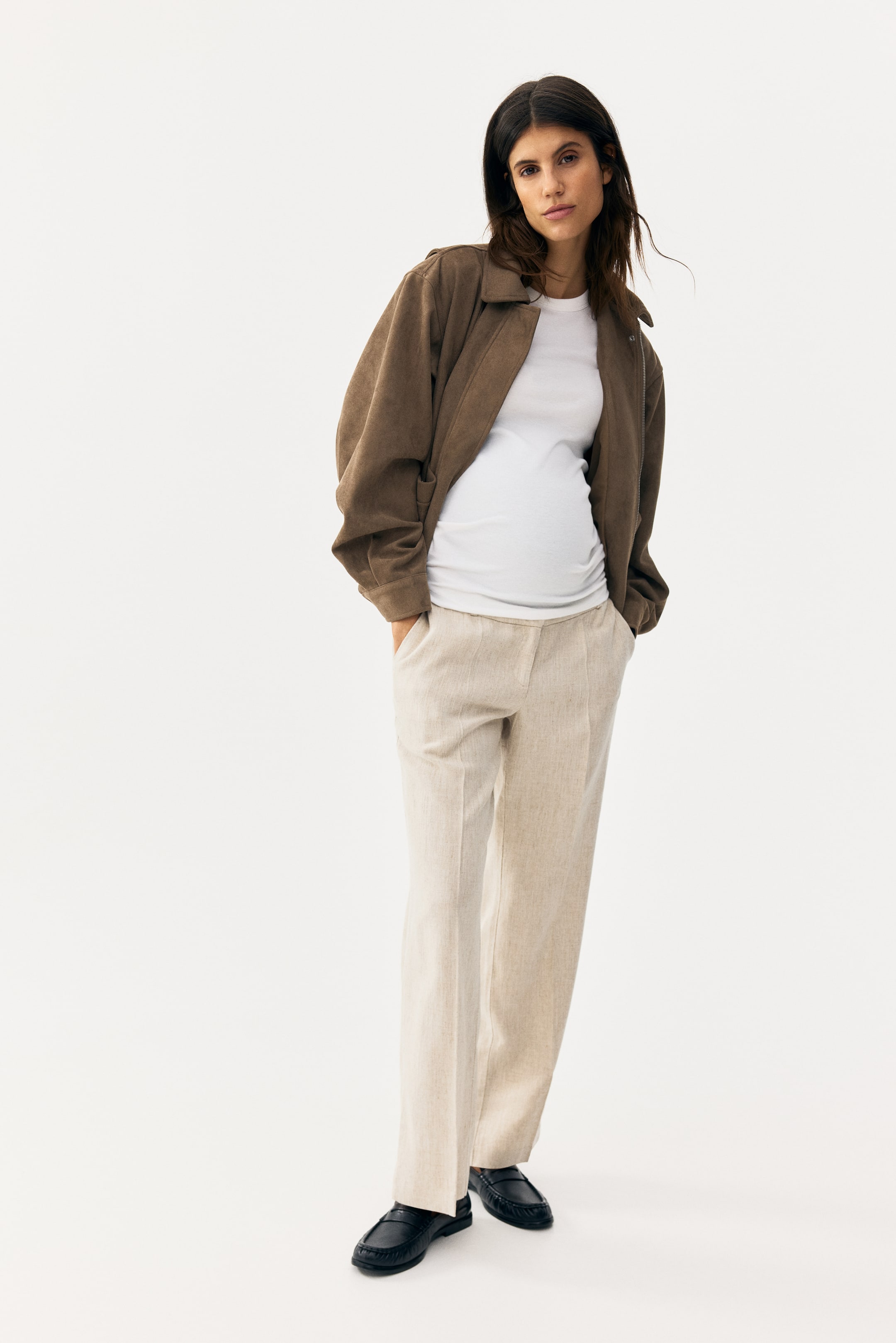 View larger image: An outfit is showcasing a brown textured relaxed-fit jacket, which is displaying a wide collar, dropped shoulders, and front patch pockets. This jacket is being layered open over a white fitted crew-neck maternity top, which is showing ruched side seams. The ensemble is being completed with light beige straight-leg trousers, which are featuring a maternity waistband and front creases, and black textured loafers, which are displaying a chunky sole.