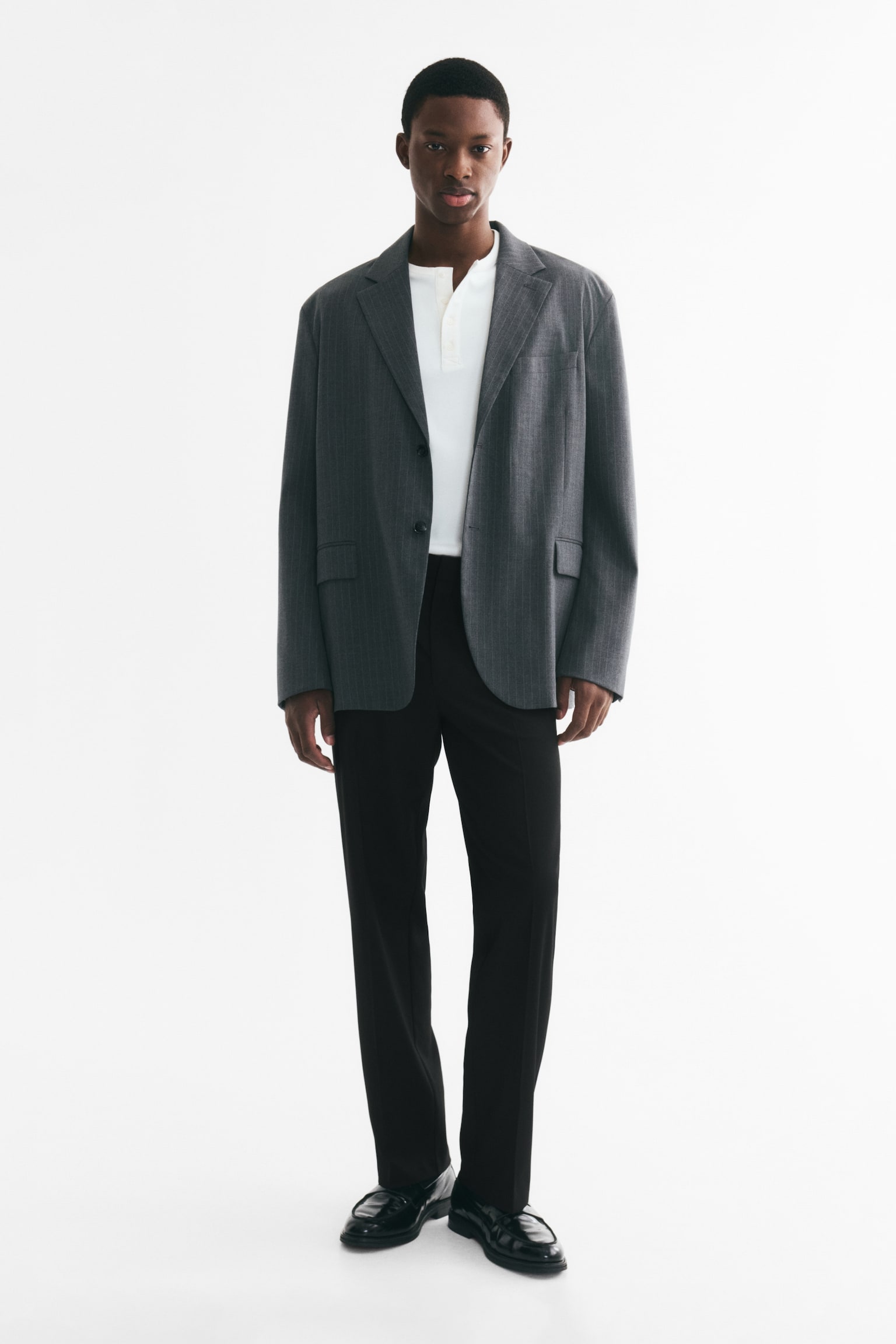 Black trousers hang front-facing, showcasing a flat front waistband with belt loops. Designed with a straight leg, they feature a prominent crease running down the centre of each leg. - 1