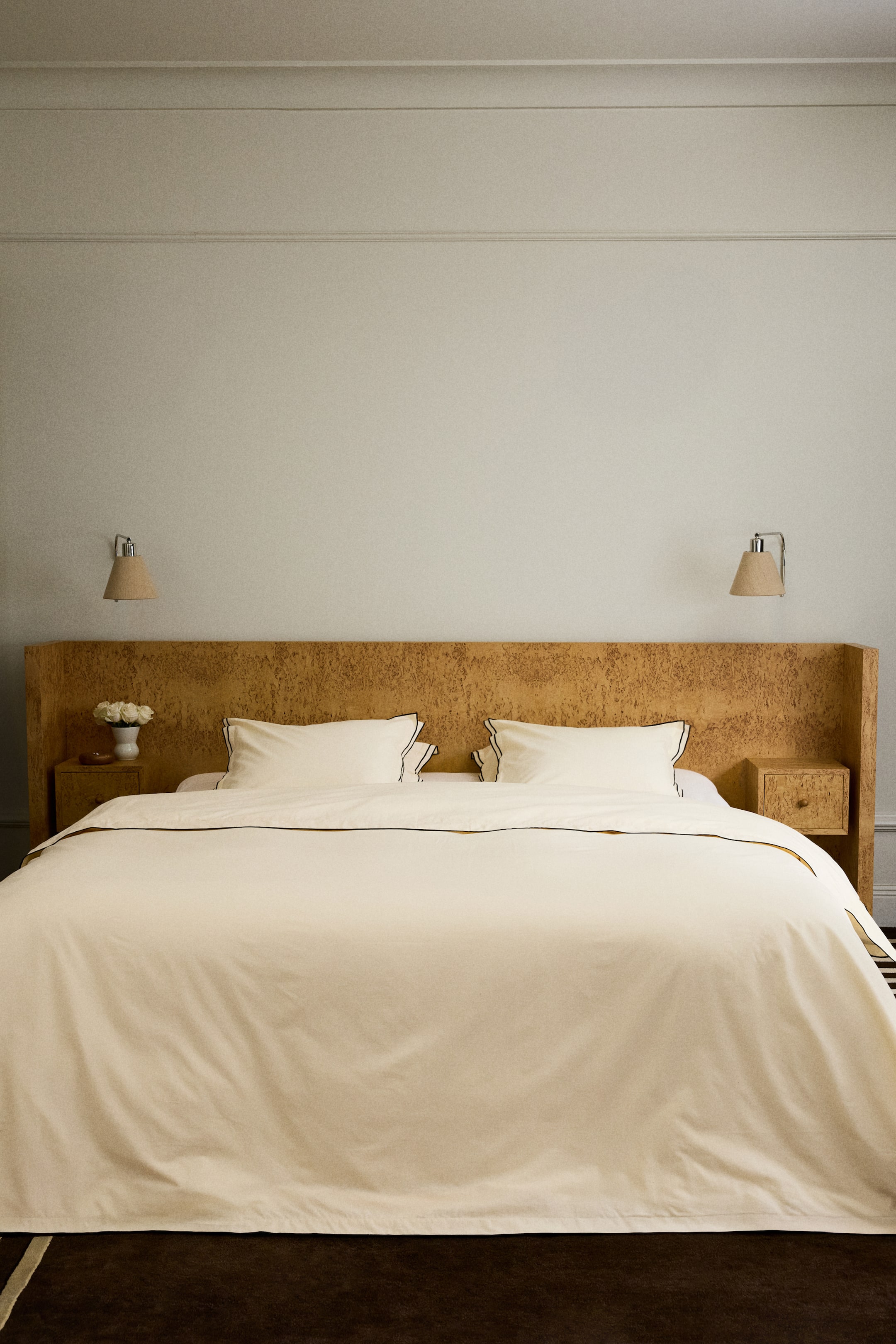 View larger image: A cream bedding set is showcased, comprising a duvet cover and two pillowcases, each adorned with dark piping along their edges.