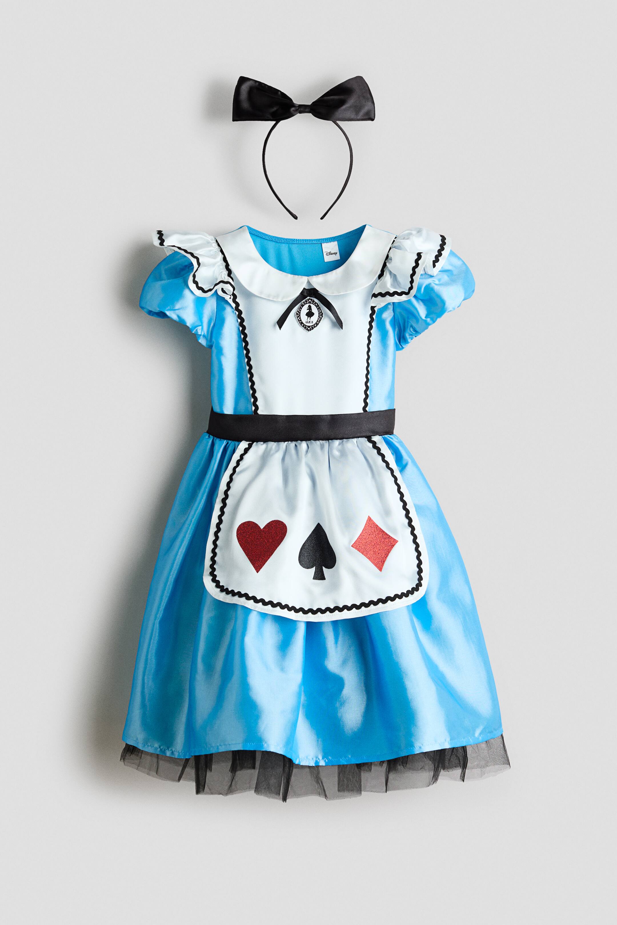 View larger image: A light blue costume dress and a black bow headband are showcased in a front view. The dress features a white Peter Pan collar, puffy short sleeves with ruffles and black trim, and a white bodice panel adorned with a black bow and emblem. A black sash accentuates the waist, sitting above a white apron with black scalloped trim that displays red heart, black spade, and red diamond playing card symbols. Black tulle peeks from the hem of the blue skirt.