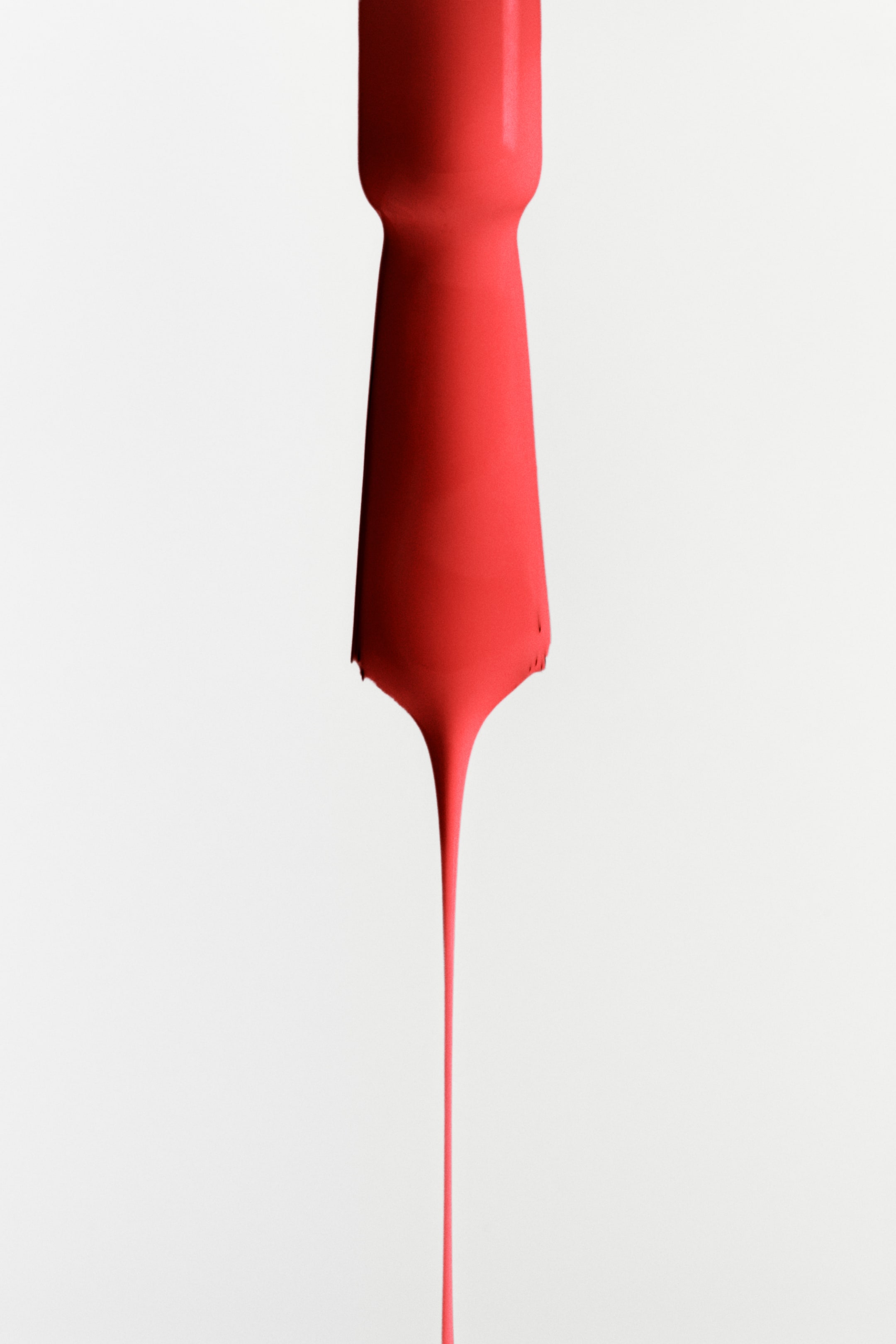 Agrandir l'image: Une peinture rouge vif forme un corps épais et allongé, se resserrant légèrement au milieu, puis se rétrécissant en une longue et fine goutte s'étendant vers le bas.