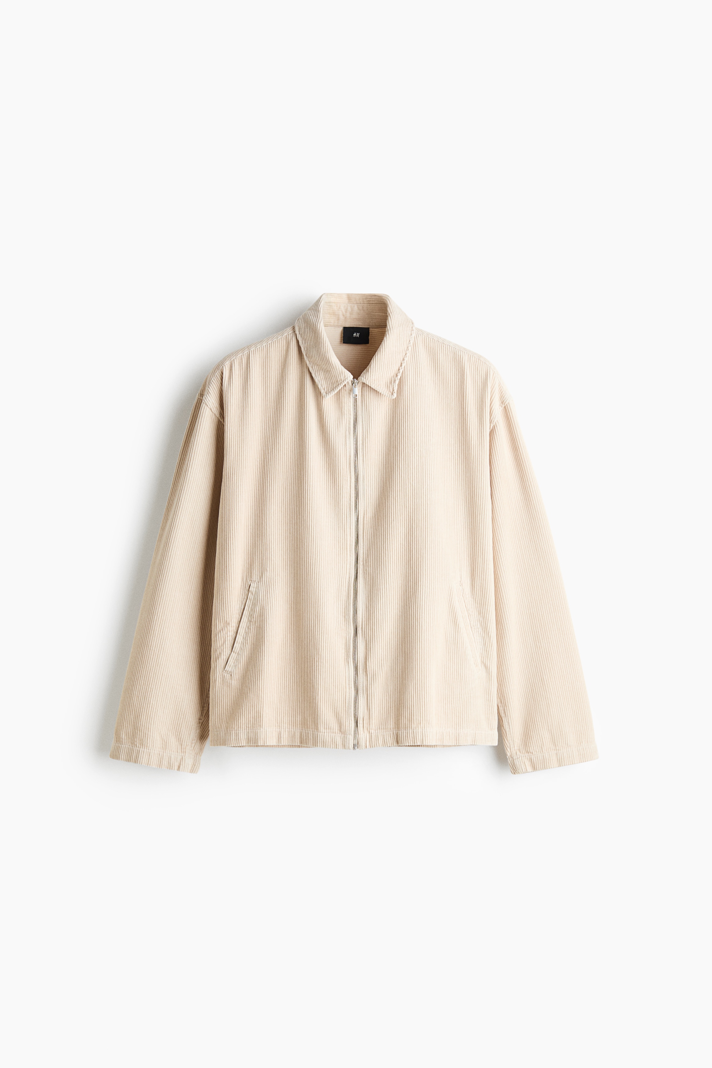 The model is wearing a cream-coloured corduroy overshirt, shown in a close-up view. The shirt features a classic collar and a metallic front zip closure.