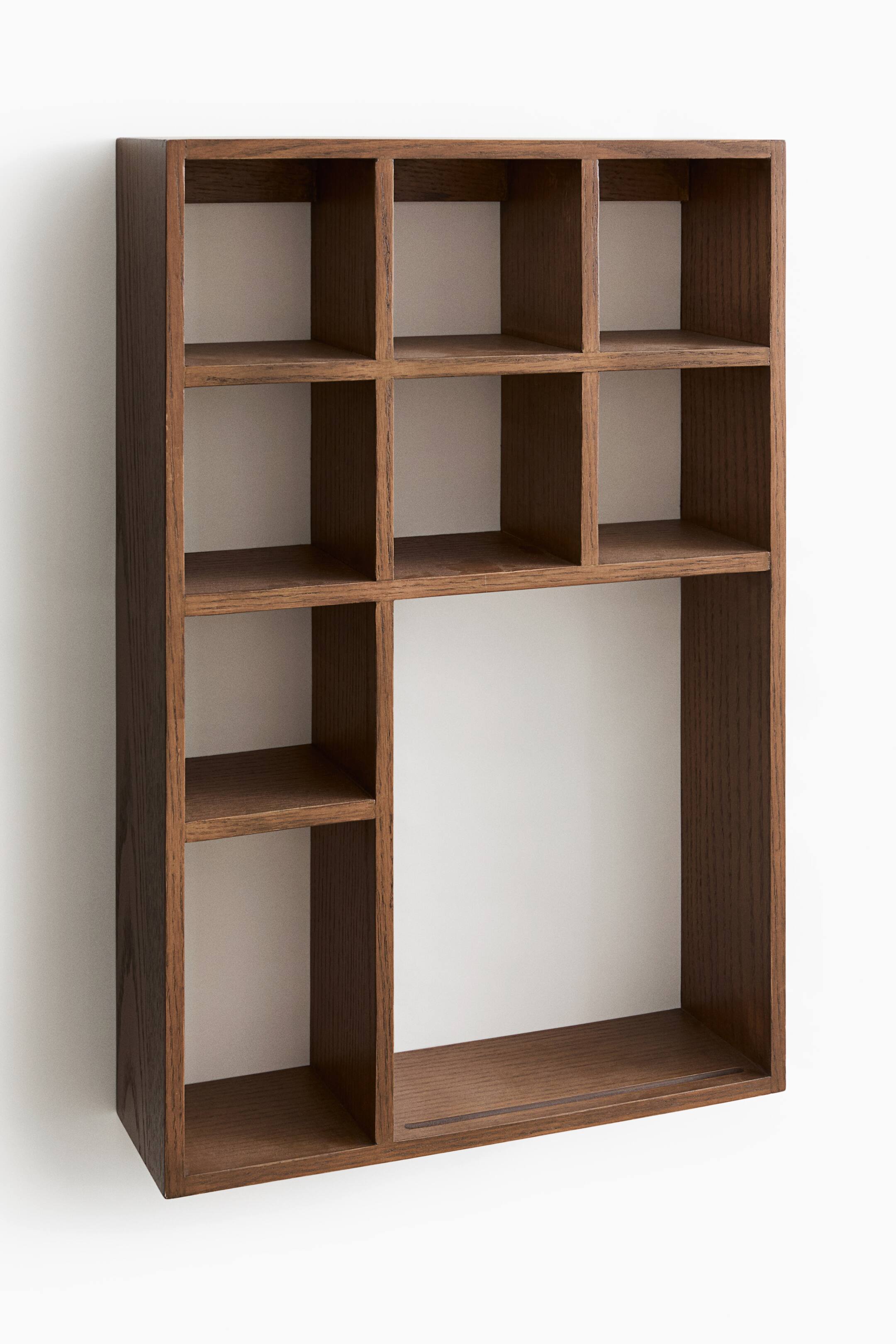 View larger image: A dark brown wood wall shelf is angled slightly to the left, showcasing its deep rectangular frame and asymmetrical grid design. The shelving unit features six small square cubbies in the top half, alongside three smaller stacked compartments in the bottom left and a single large open rectangular section in the bottom right.