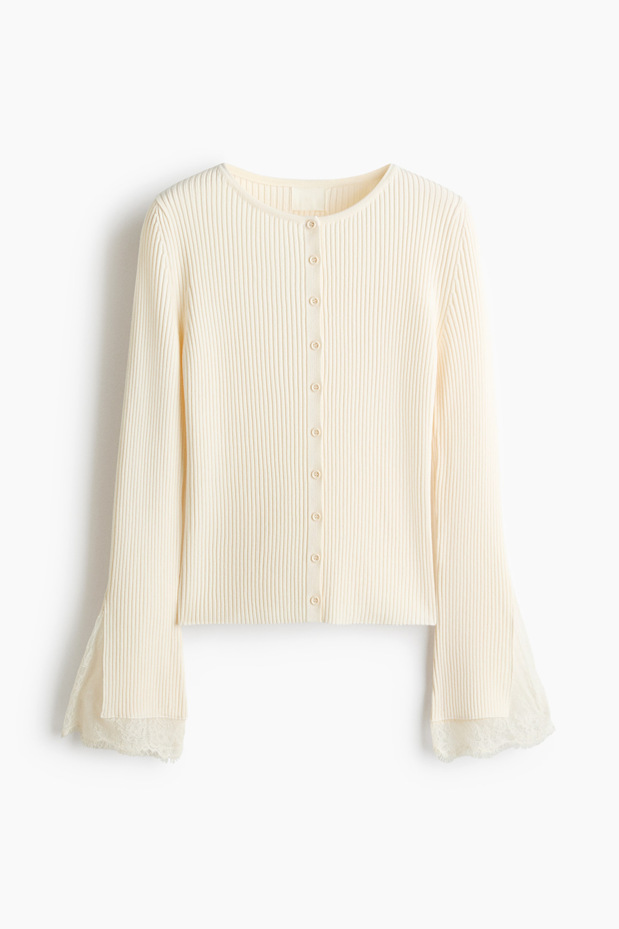 Visualizza l'immagine ingrandita: Vista frontale di un cardigan corto e aderente color crema, caratterizzato da un motivo verticale a coste lavorate a maglia, scollo rotondo e chiusura frontale con bottoni abbinati. Le maniche lunghe mostrano polsini svasati con spacchi laterali e delicata rifinitura in pizzo eyelash smerlato lungo i bordi.