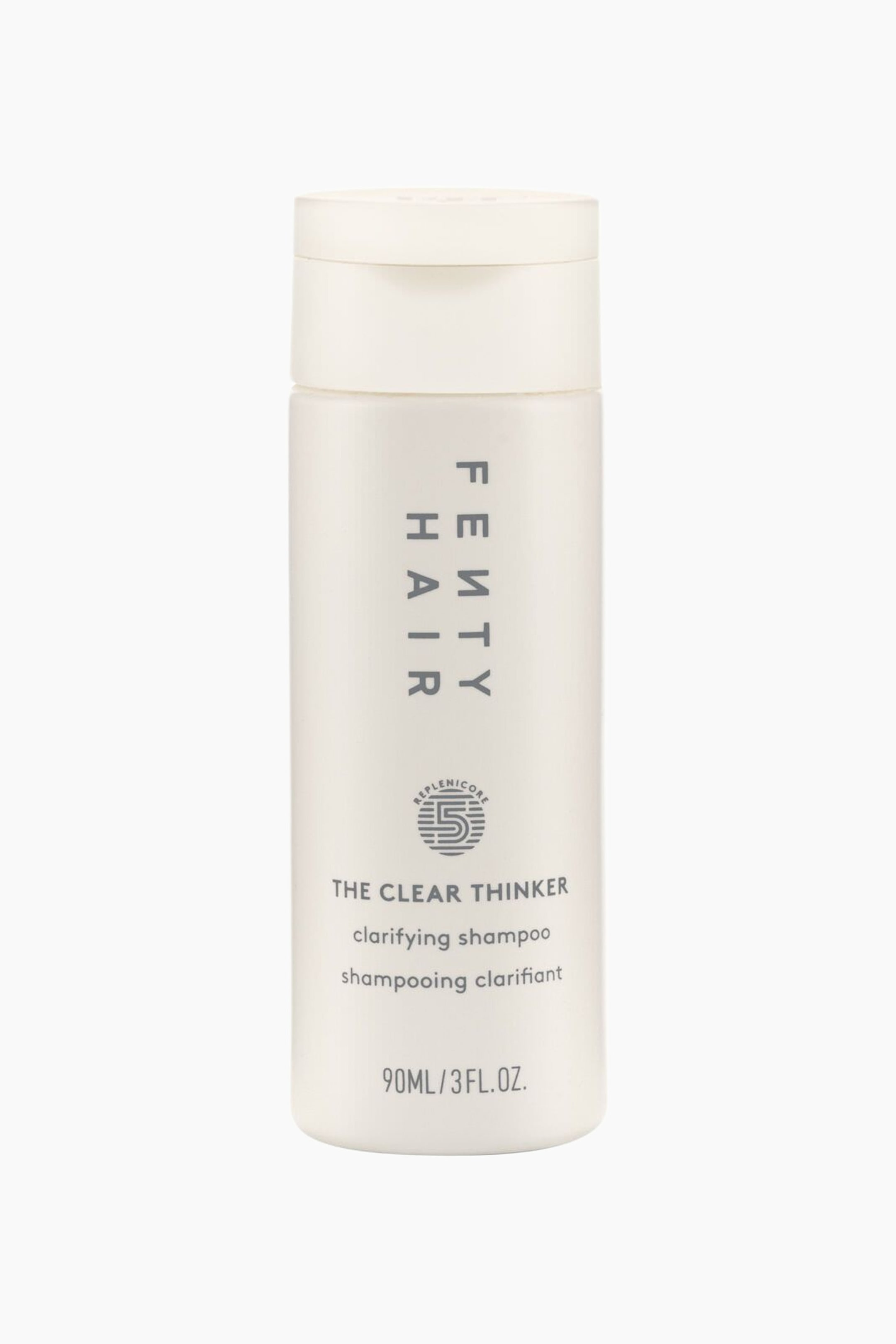 Visa större bild: En cylindrisk, matt benvit flaska med Fenty Hair "The Clear Thinker" djuprengörande schampo står upprätt och vänd framåt. Flaskan visar vertikal grå "FENTY HAIR"-branding, en cirkulär "Replenicore 5"-logotyp och produktdetaljer under ett matchande flip-top-lock.