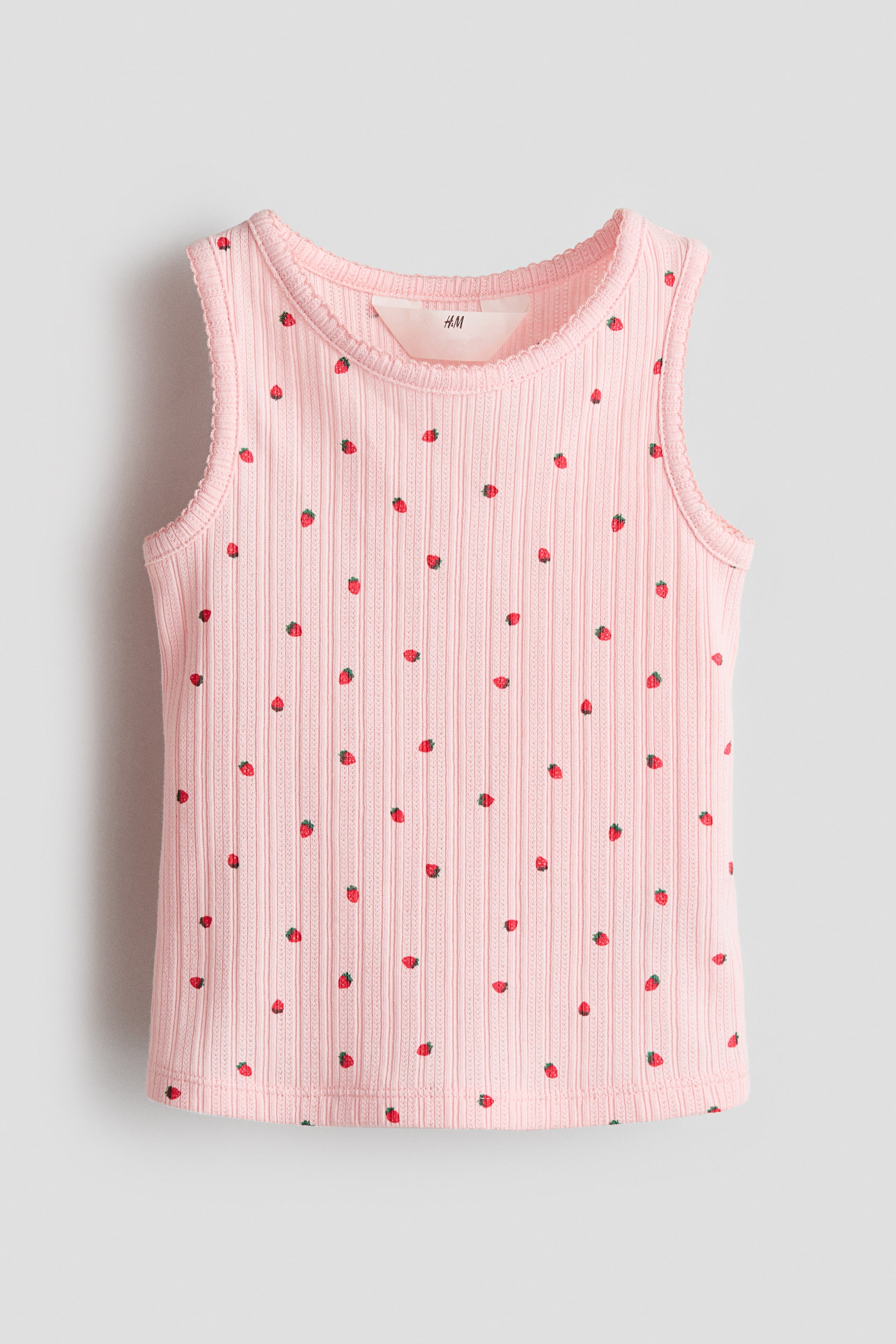 View larger image: "The front view of a pink ribbed tank top is on display. It boasts an all-over small strawberry print on its ribbed knit fabric, and features a round neckline along with sleeveless armholes, both enhanced with a scalloped trim."