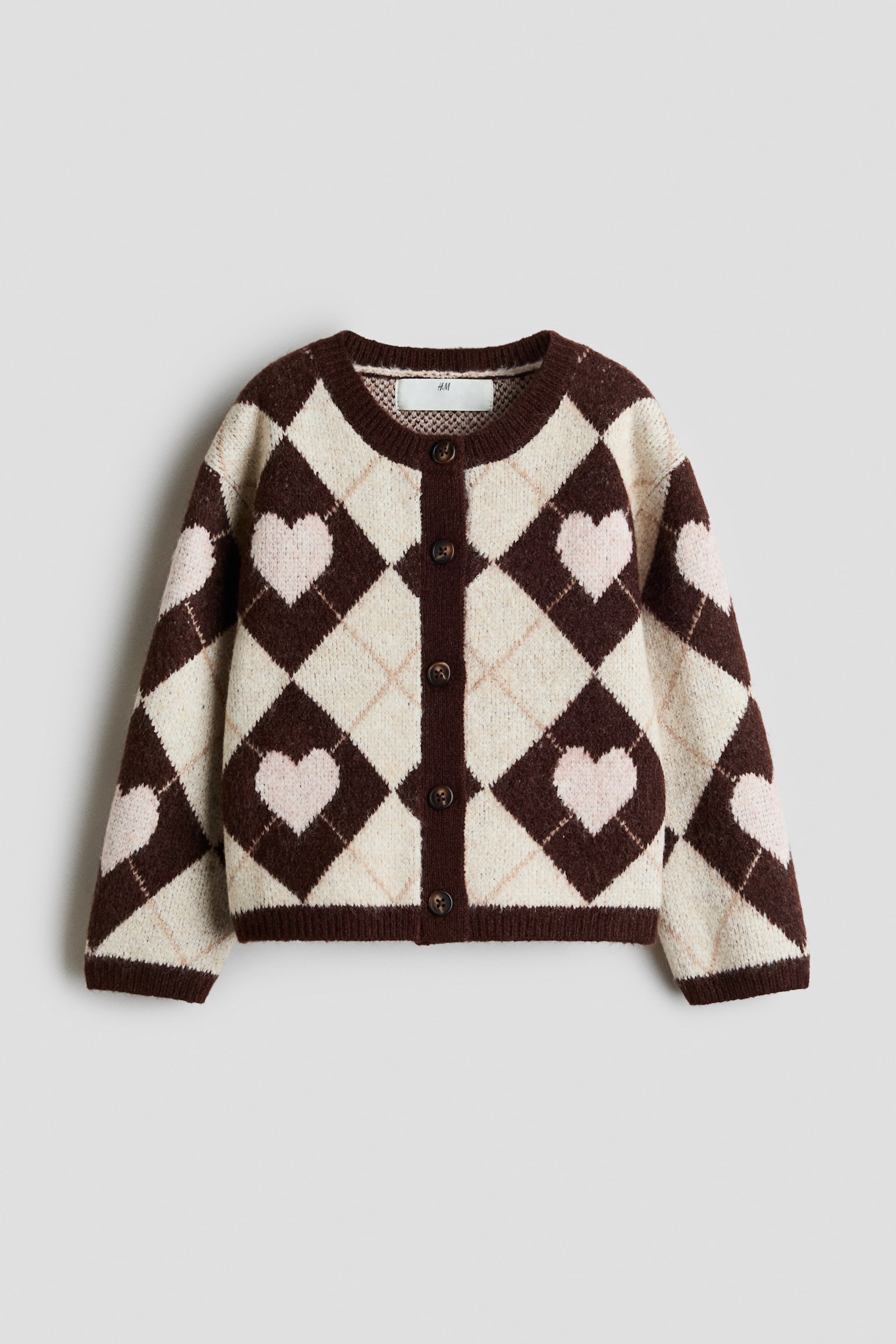 This knit cardigan, shown from the front, features a dark brown and cream argyle pattern with pale pink hearts nested inside the dark diamonds. It has a round neckline, a button-up front with dark buttons, and ribbed trim on the collar, cuffs, and hem.