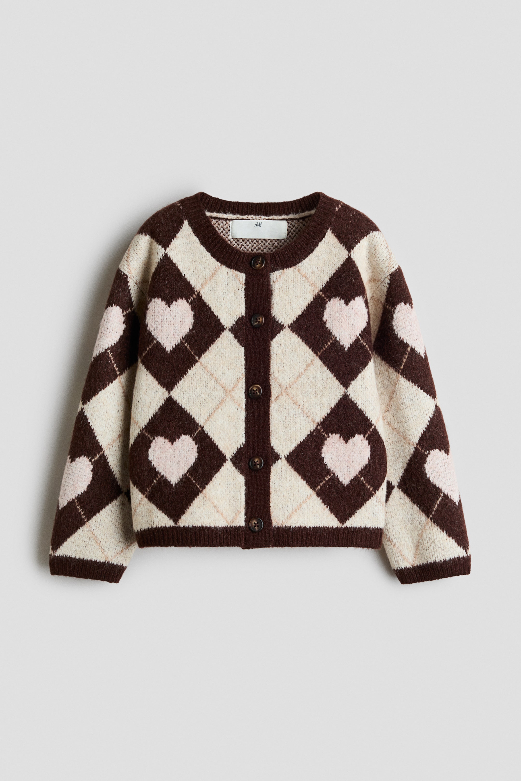 View larger image: This knit cardigan, shown from the front, features a dark brown and cream argyle pattern with pale pink hearts nested inside the dark diamonds. It has a round neckline, a button-up front with dark buttons, and ribbed trim on the collar, cuffs, and hem.