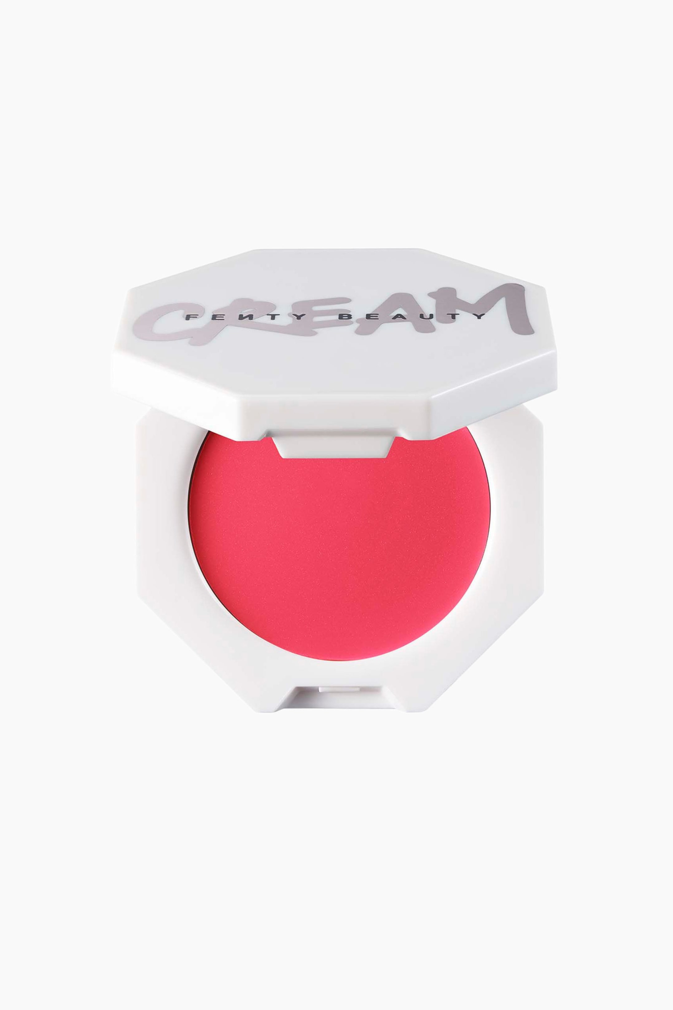 Näytä suurempi kuva: Cheeks Out Freestyle Cream Blush näkyy avoimessa valkoisessa kahdeksankulmaisessa rasian muodossa suoraan eteenpäin suunnattuna. Rasia paljastaa pyöreän pannullisen elinvoimaista pinkkiä voidemaista poskipunaa, ja osittain nostettu kansi näyttää sanan ”CREAM” tyylitellyllä violetilla graffiti-tyylisellä fontilla, jonka yli on painettu ”FENTY BEAUTY”.