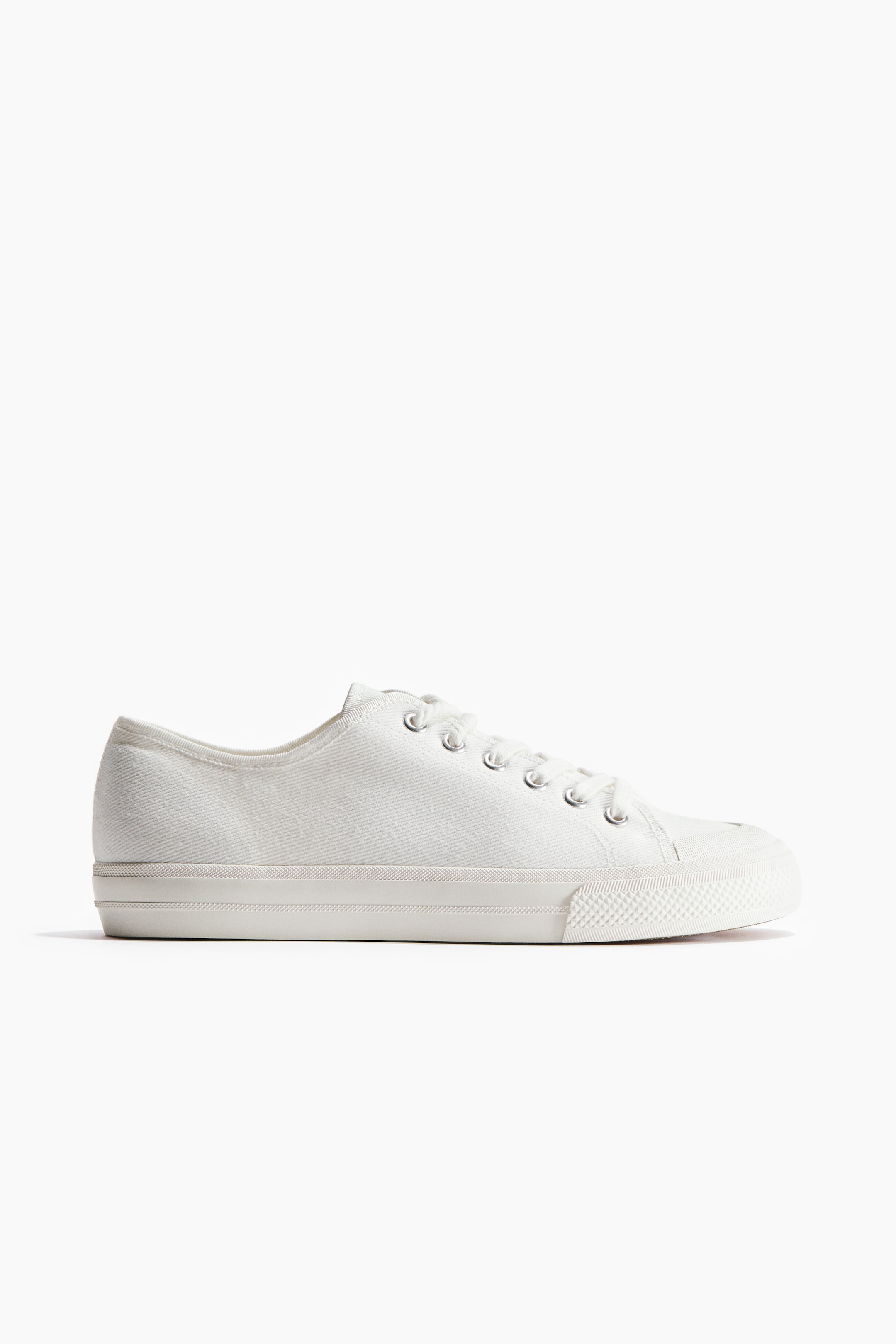 Größeres Bild anzeigen: Ein weißer Sneaker wird von der Seite präsentiert, mit Obermaterial aus Baumwolltwill und Schnürung vorne. Er ist mit vulkanisierten Gummisohlen ausgestattet.