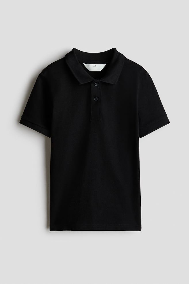 A black polo shirt is facing front, showcasing a pointed collar, a two-button placket with black buttons, and short sleeves with ribbed cuffs. A white H&M label is visible at the back of the neck. - 1