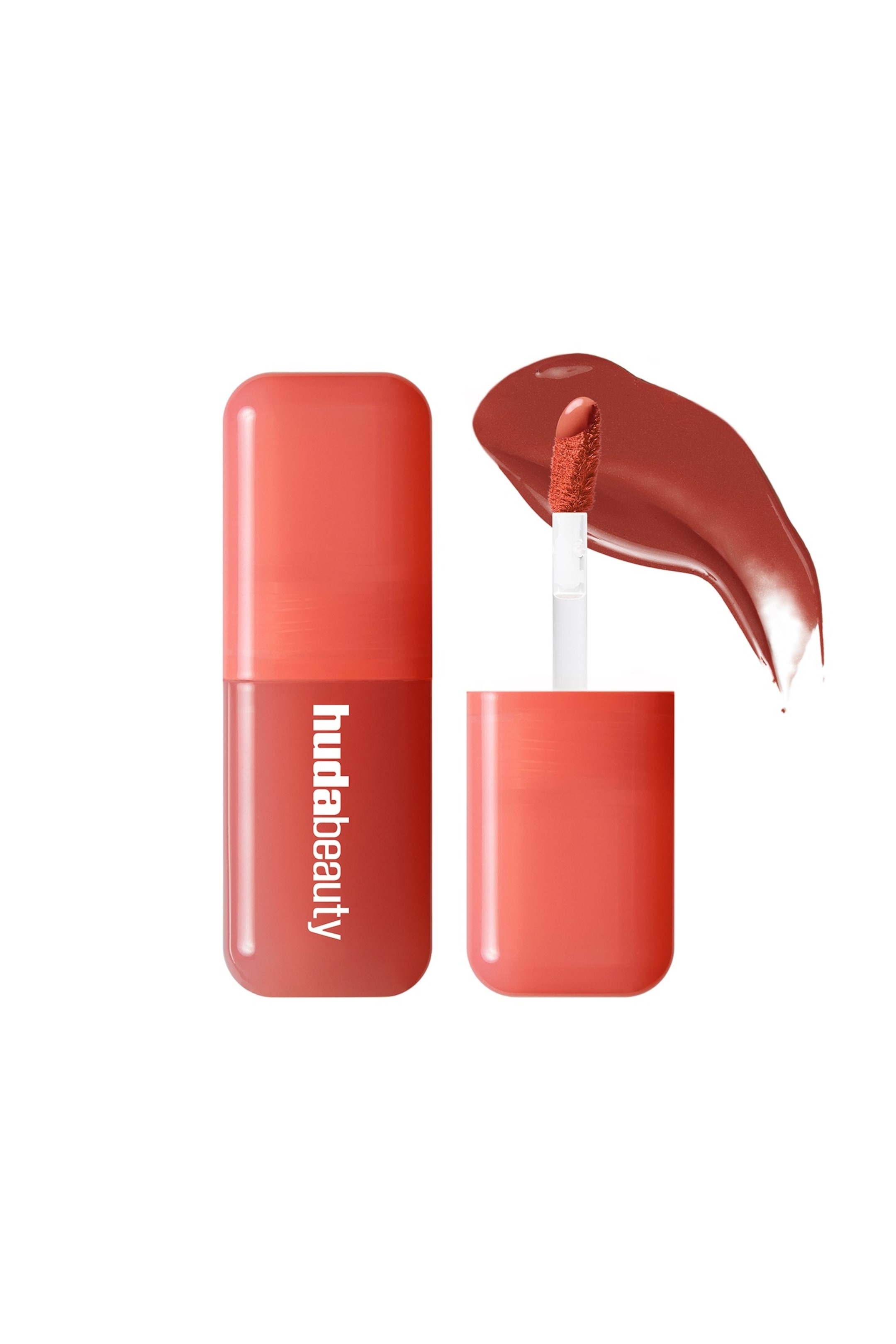 Vis større bilde: Et Huda Beauty leppeprodukt har en tofarget rektangulær beholder med avrundede kanter, som viser en mørkere korallnyanse nederst og en lysere korallhette, med "hudabeauty"-logoen i hvitt. En hvit applikator med en lodden, spiss tupp hviler på en S-formet prøve av det rike rødbrune flytende produktet.