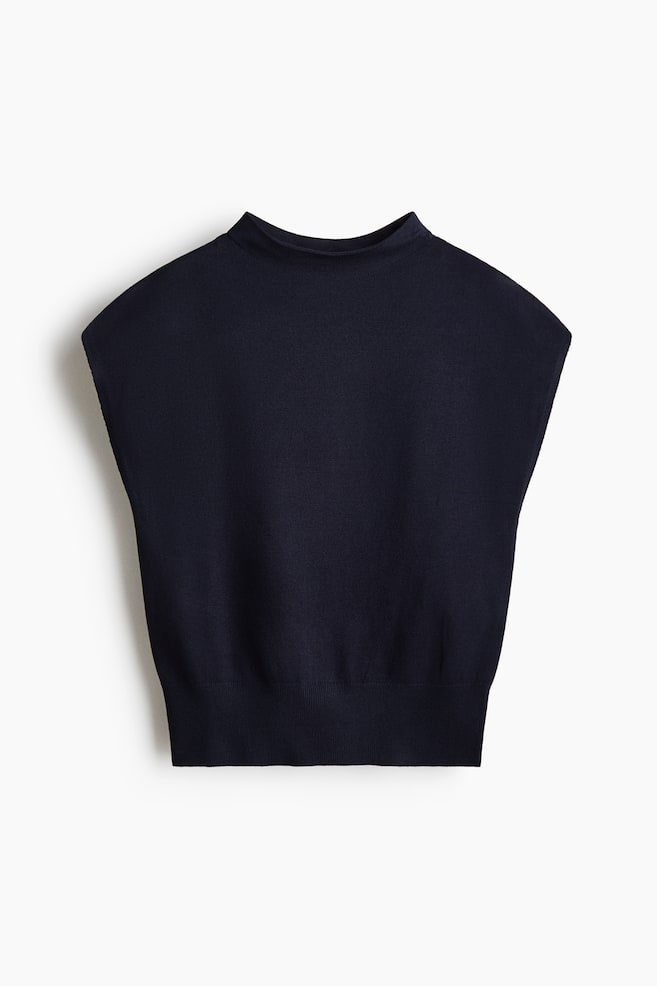 A dark blue sleeveless knit top is featuring a mock neck and a ribbed hem, presented from a front view. - 1